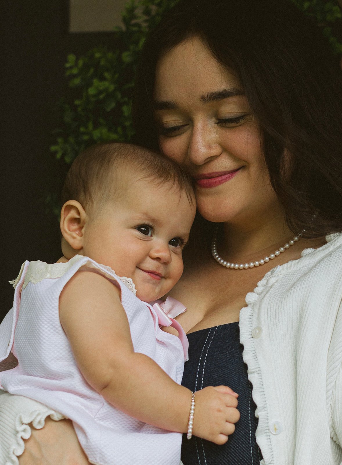 Mother holding her smiling baby daughter for a natural family portrait outside their New Orleans home.