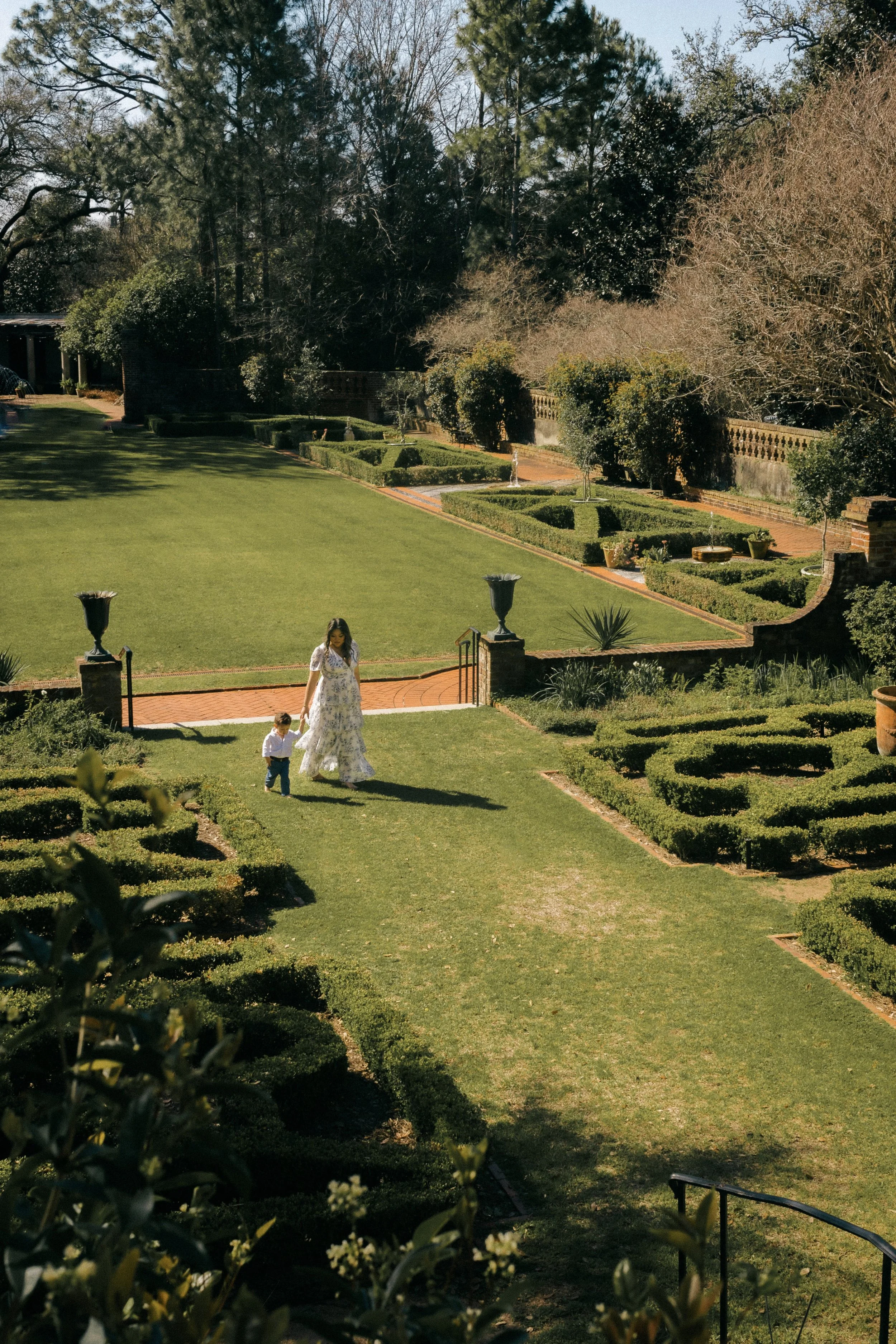 Joyful mother and child walking through the gardens at Longue Vue in Metairie during a family photo session.