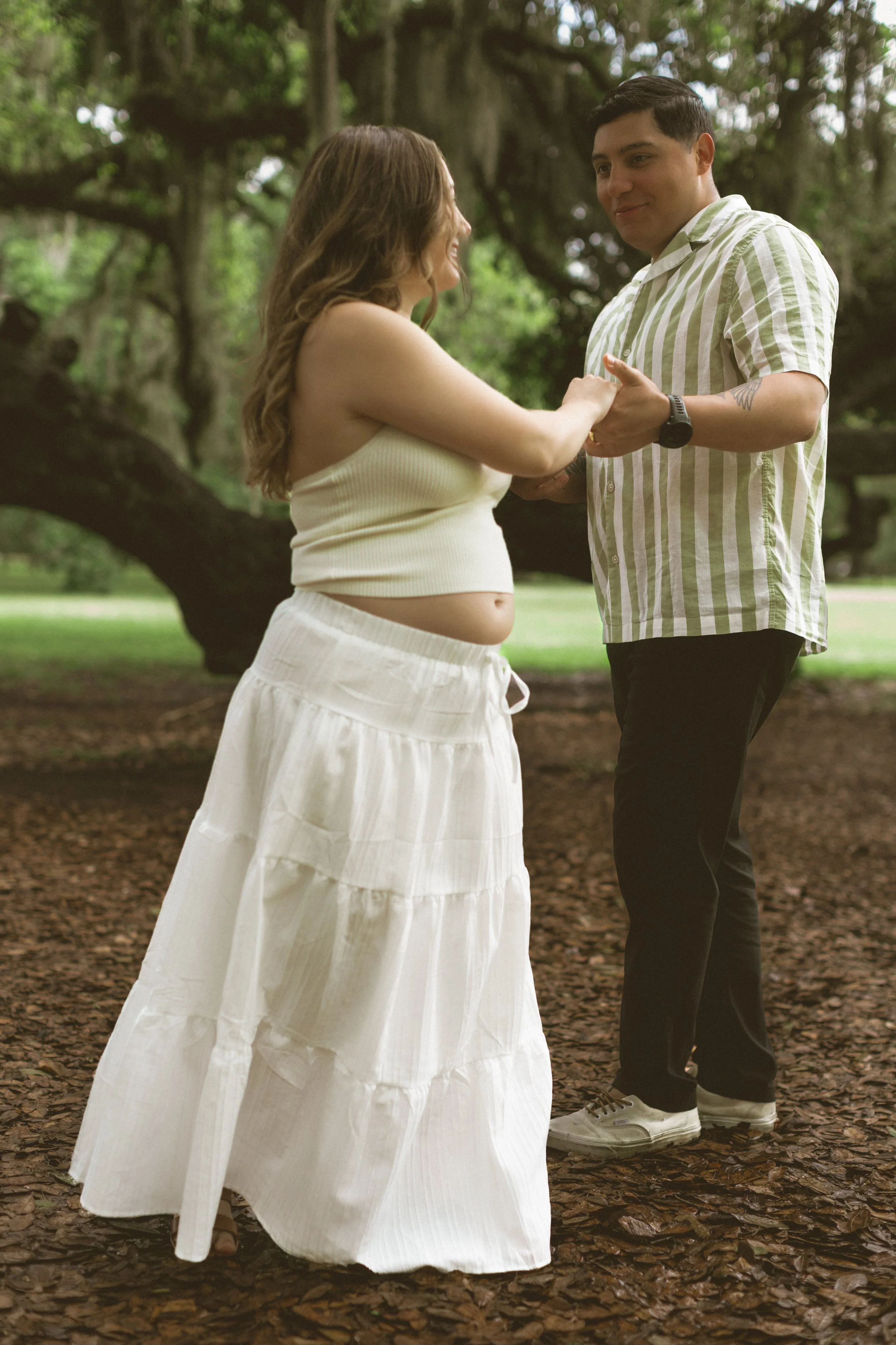 Intimate maternity photo of expecting parents holding hands outdoors in New Orleans.