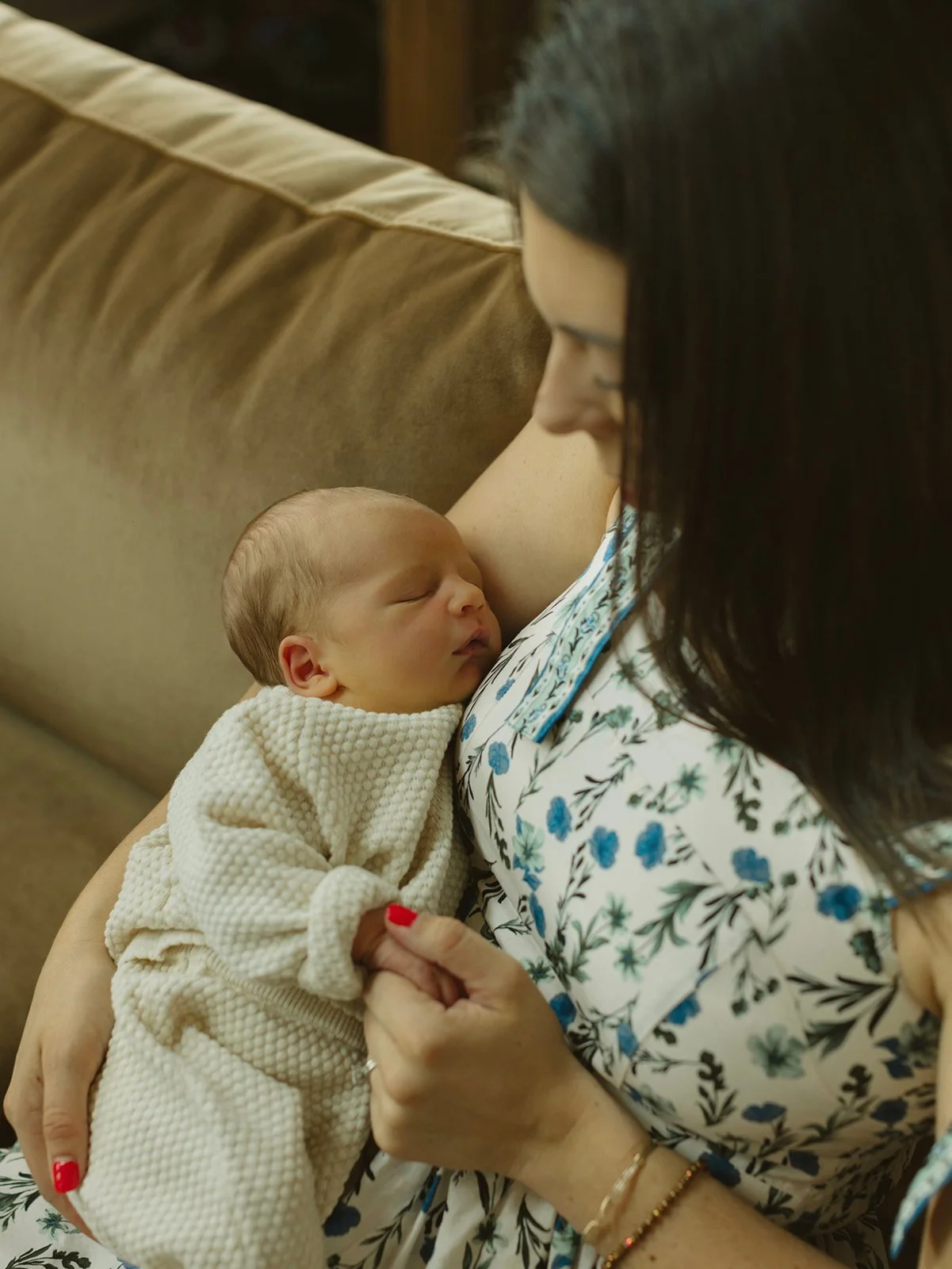 Mother cuddling newborn during a quiet lifestyle family photo session at home.