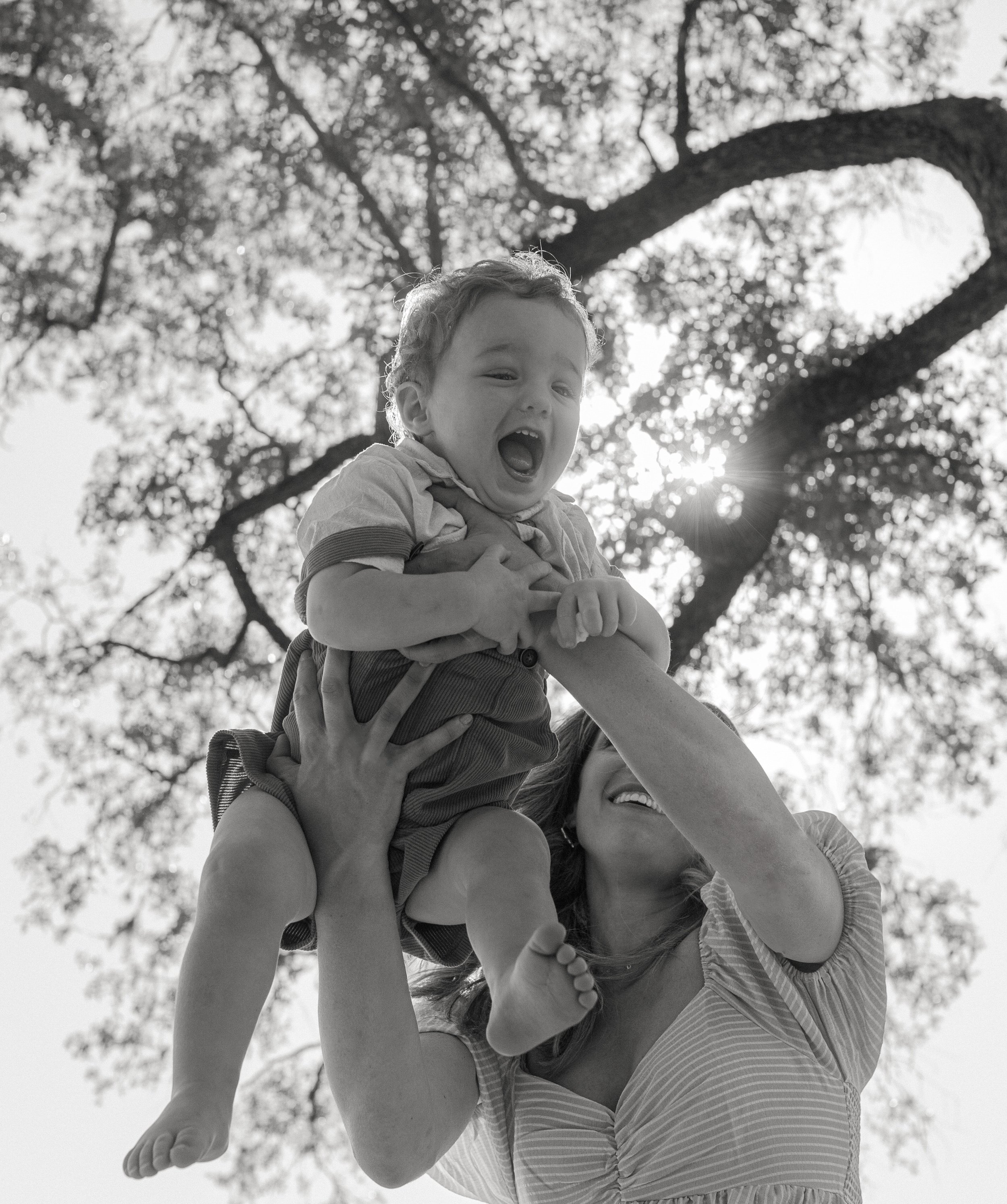 A warm, golden-hour family session in New Orleans' iconic City Park. This heartfelt photo captures a tender moment as parents hold hands with their young children beneath the sprawling oak trees. The family is framed by soft sunlight filtering throug