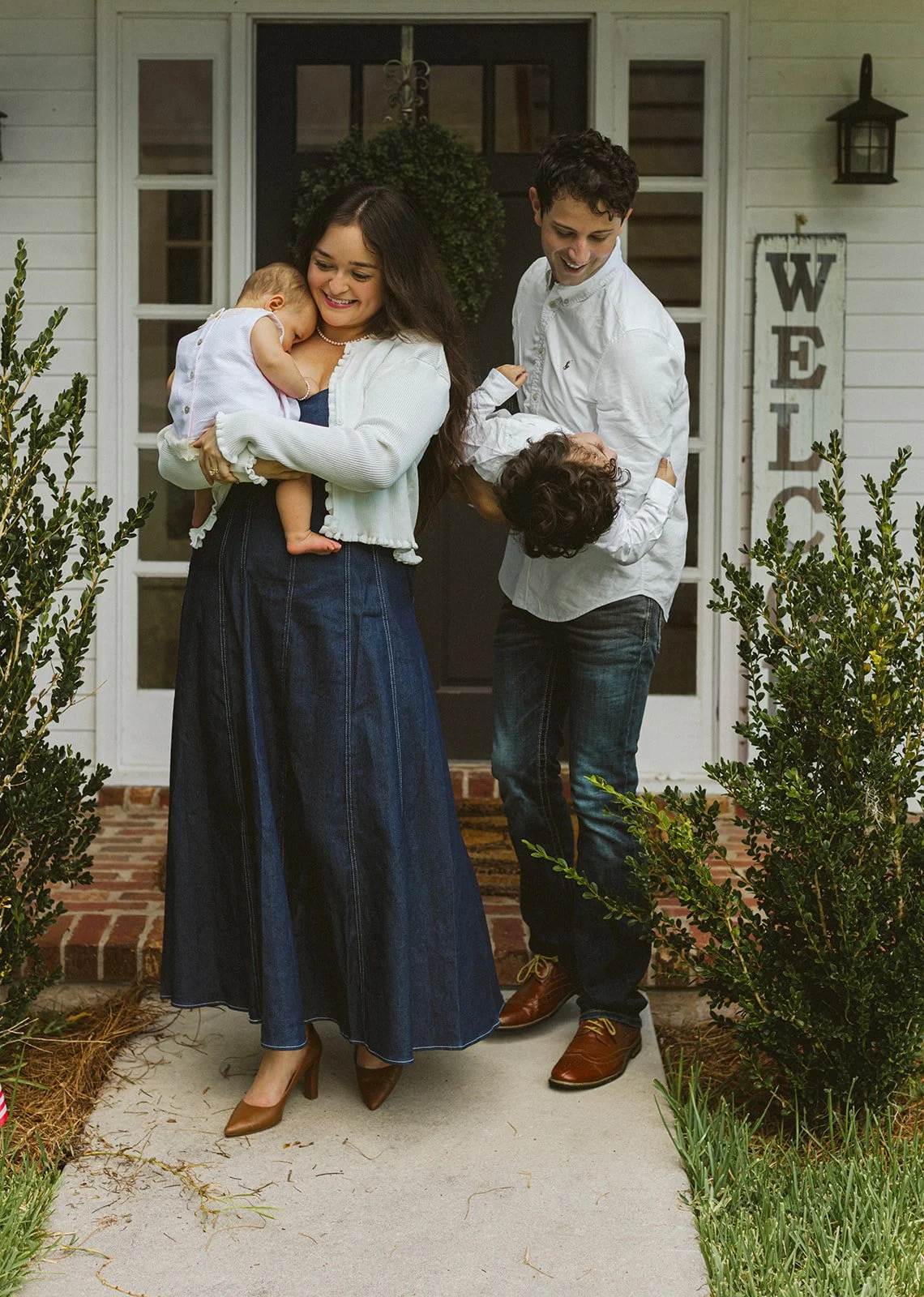 Family of four sharing a playful moment together on the front porch of their New Orleans home.