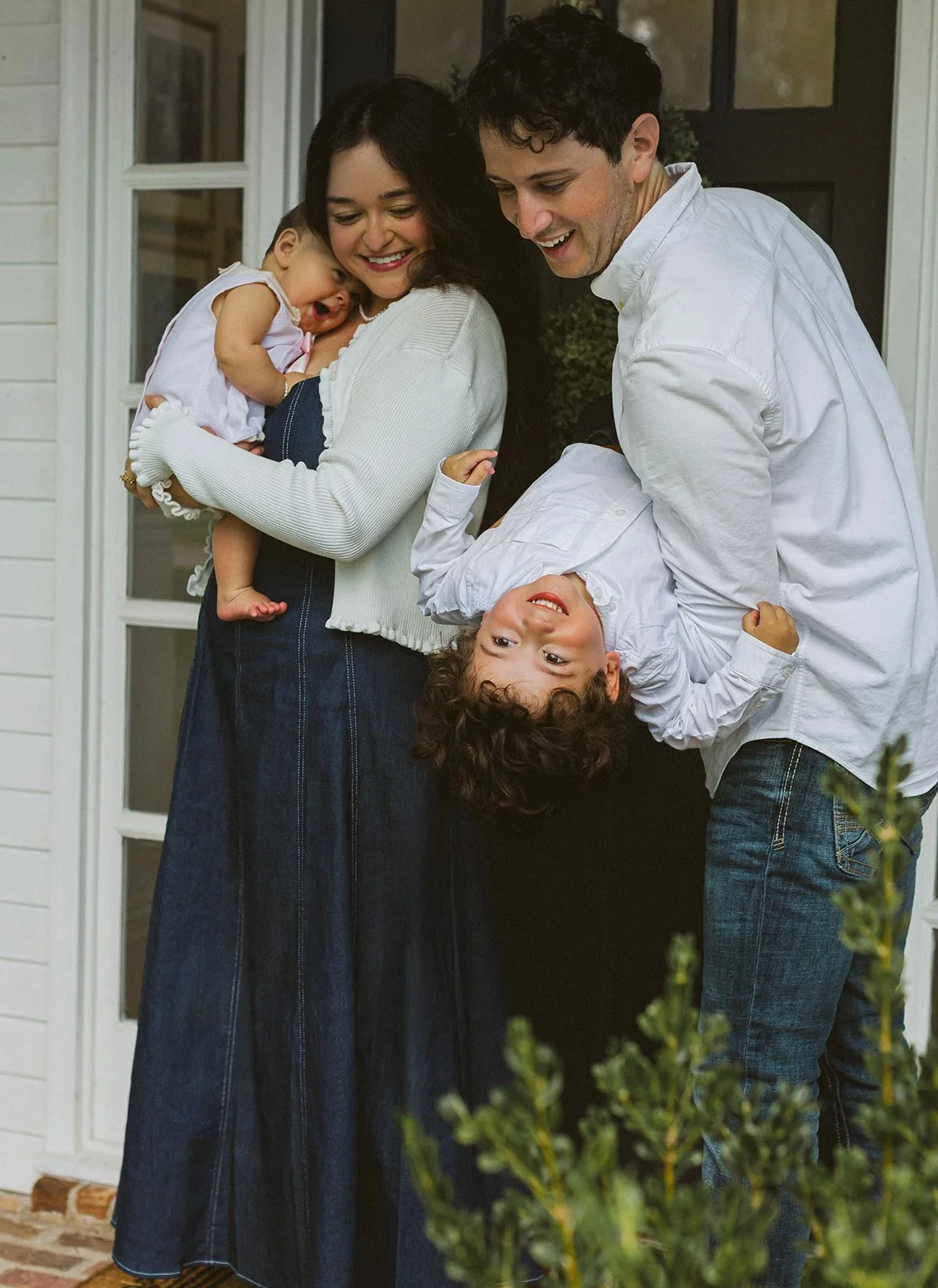 Parents laughing with their two children during an outdoor family portrait at their New Orleans home.