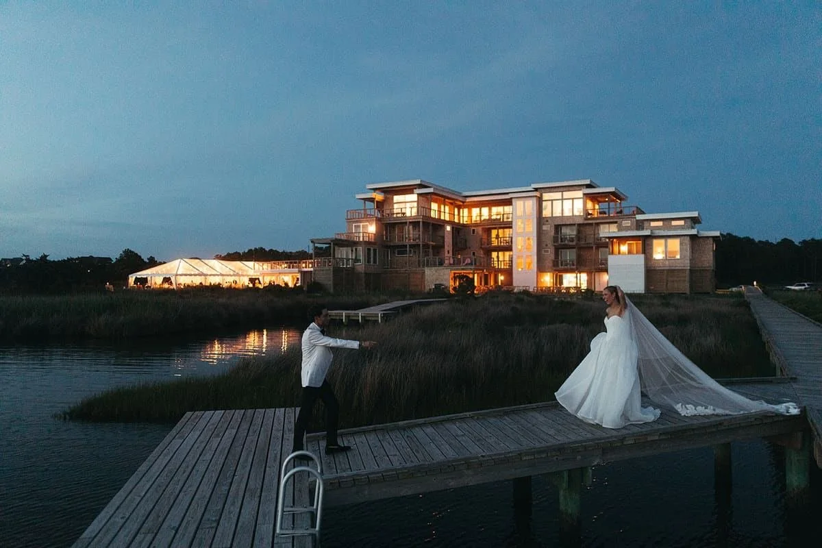 The flagship house at Edgecamp at blue hour on Hatteras Island, the wedding tent lit beside it.