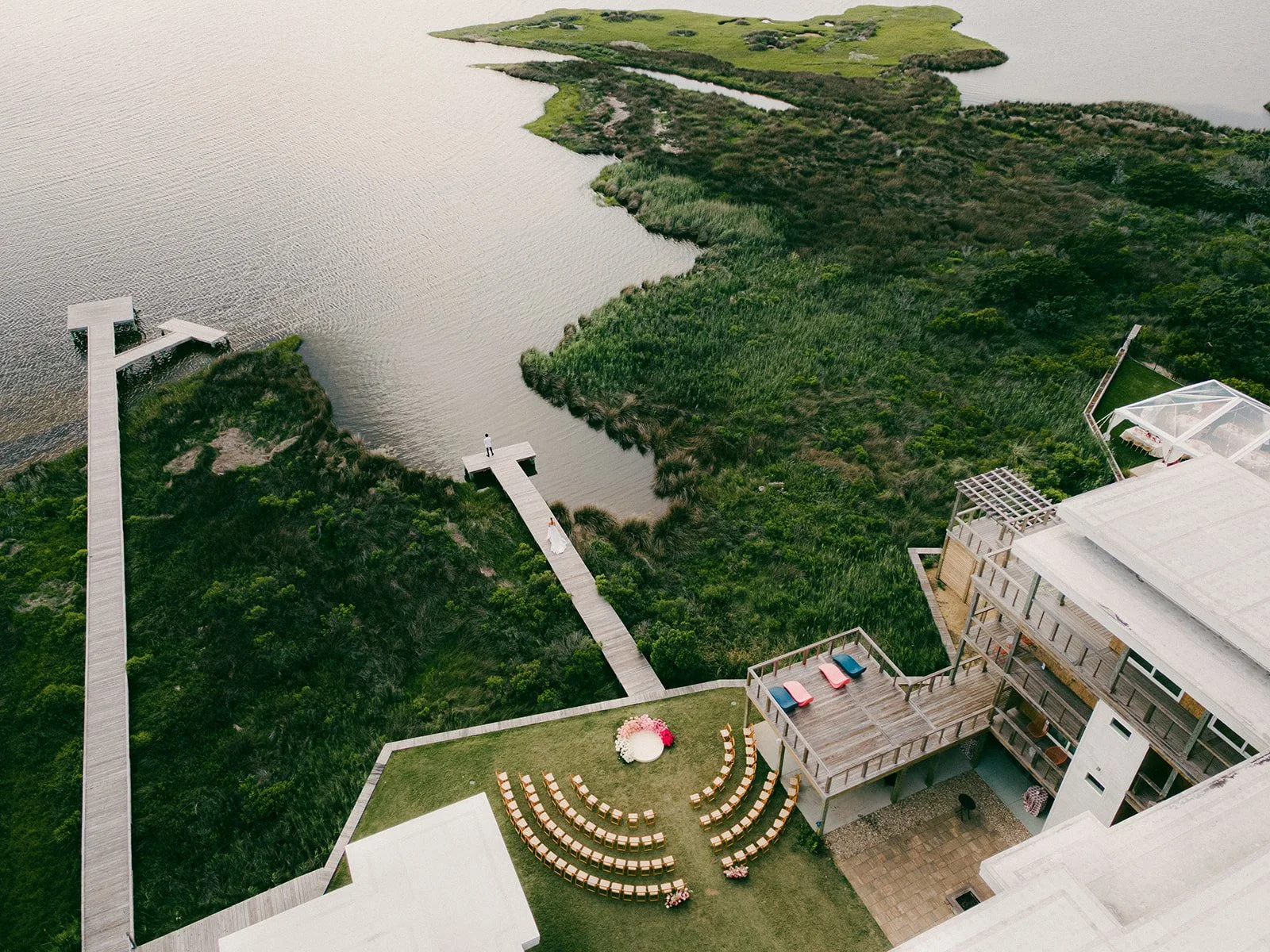 Aerial view of a lawn wedding ceremony at Edgecamp on Hatteras Island, with the dock and Pamlico Sound behind