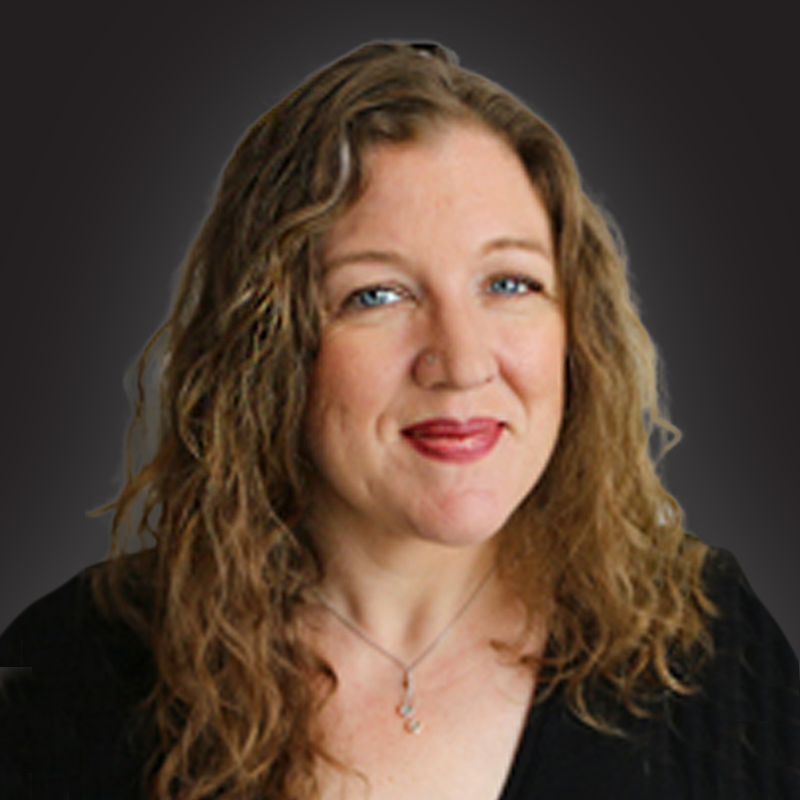 A woman with curly, light brown hair and blue eyes smiling at the camera, wearing a black top and a silver necklace, against a dark gray background.