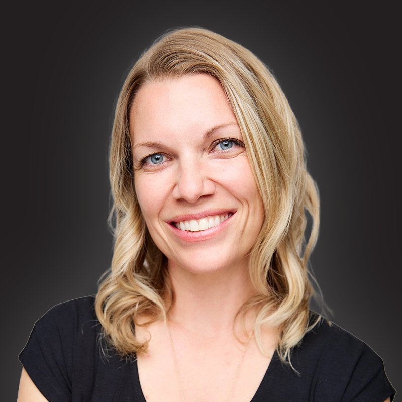 Headshot of a smiling woman with wavy blonde hair and blue eyes, wearing a black top, against a dark gradient background.