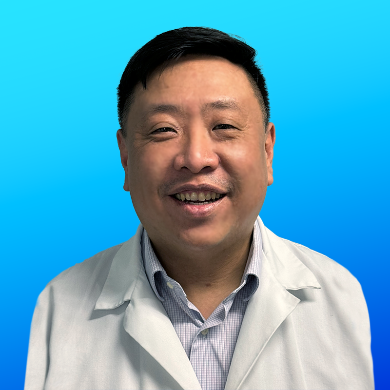 Man in a lab coat smiling against a blue gradient background.