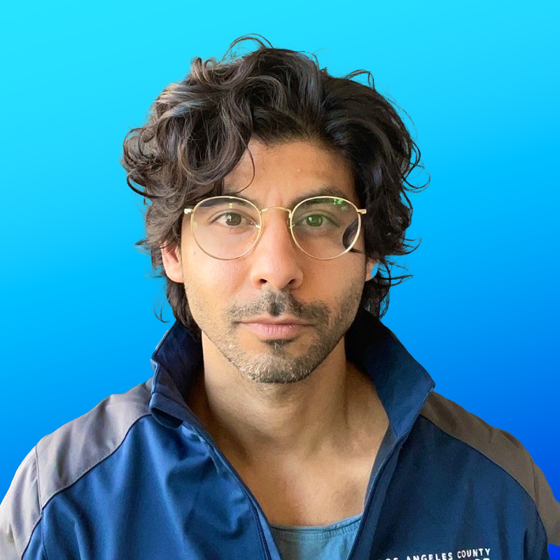 Mercy Mental Health - Person with curly hair wearing glasses and a blue jacket against a blue gradient background.