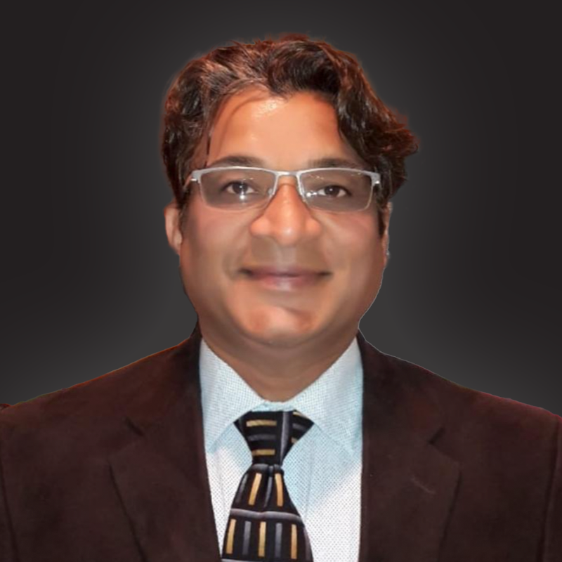 Professional headshot of a man with glasses, wearing a dark suit, white shirt, and striped tie, smiling against a dark background.