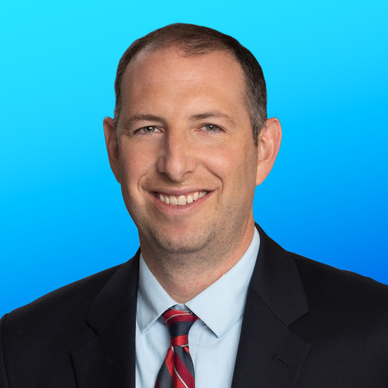 Man in suit and tie smiling, blue background