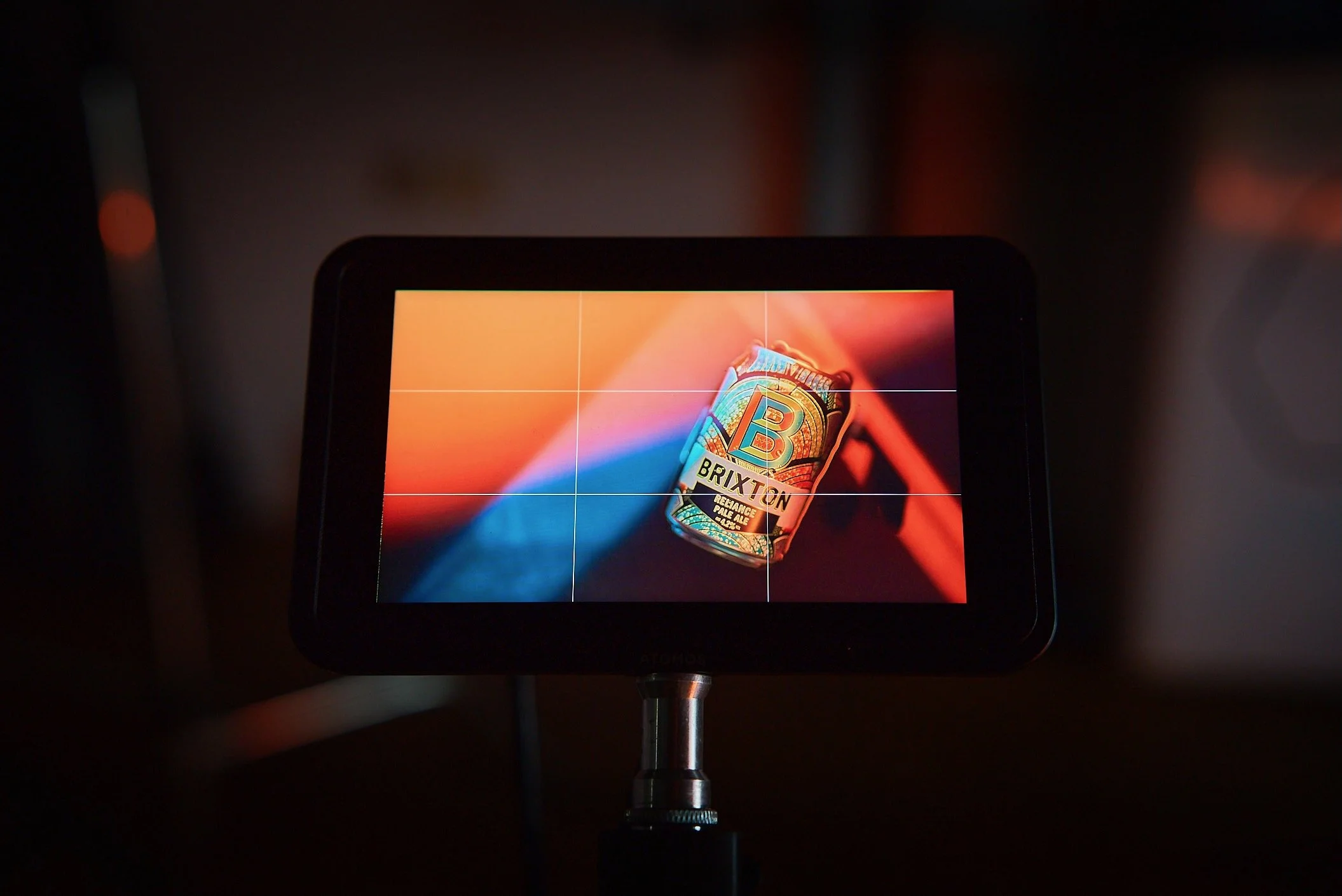 A camera screen displaying an image of a can of Brixton beer, with a colorful background and grid lines for framing.