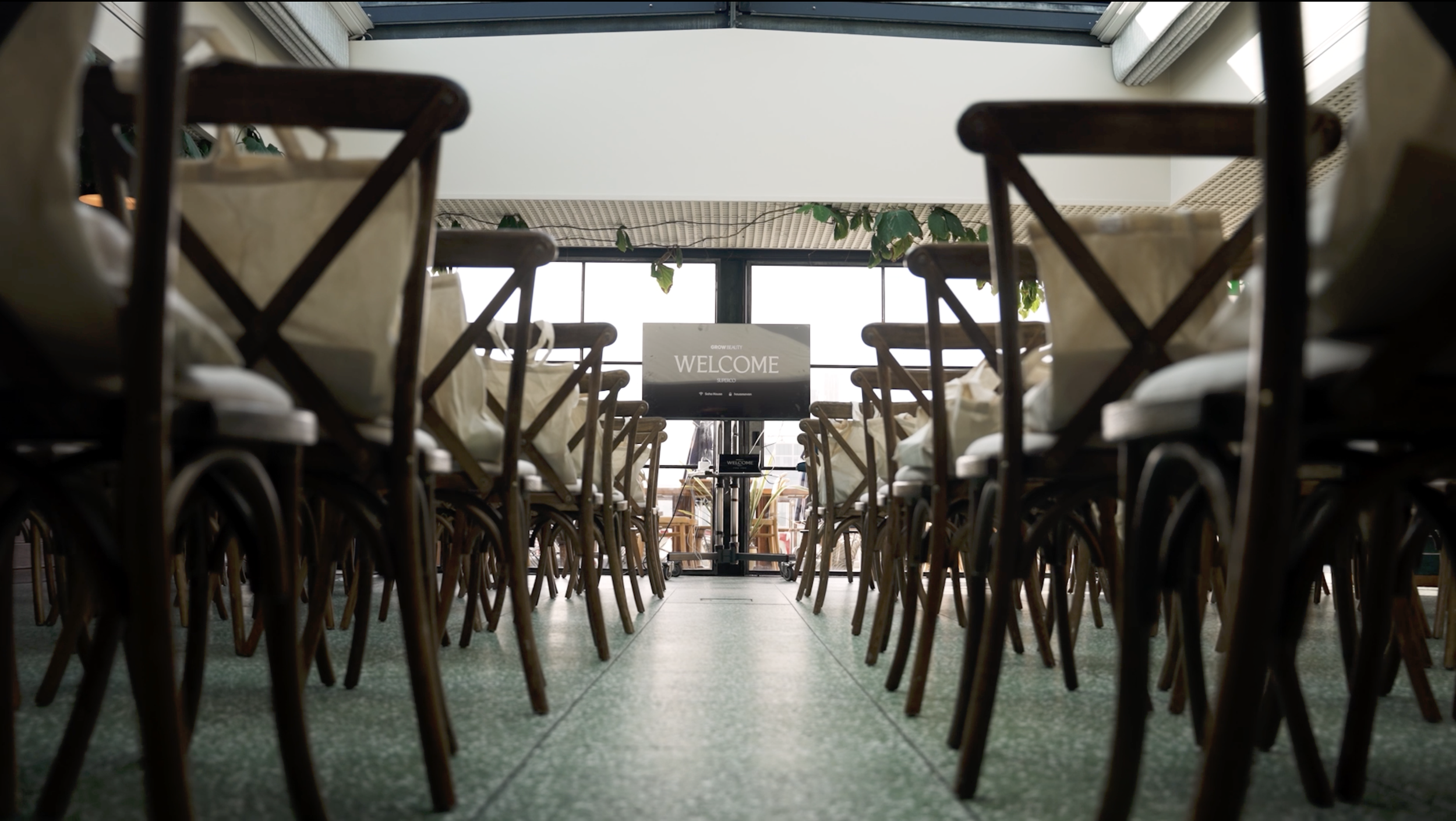 Indoor restaurant or event space with rows of tables and chairs facing a reception or presentation area with a