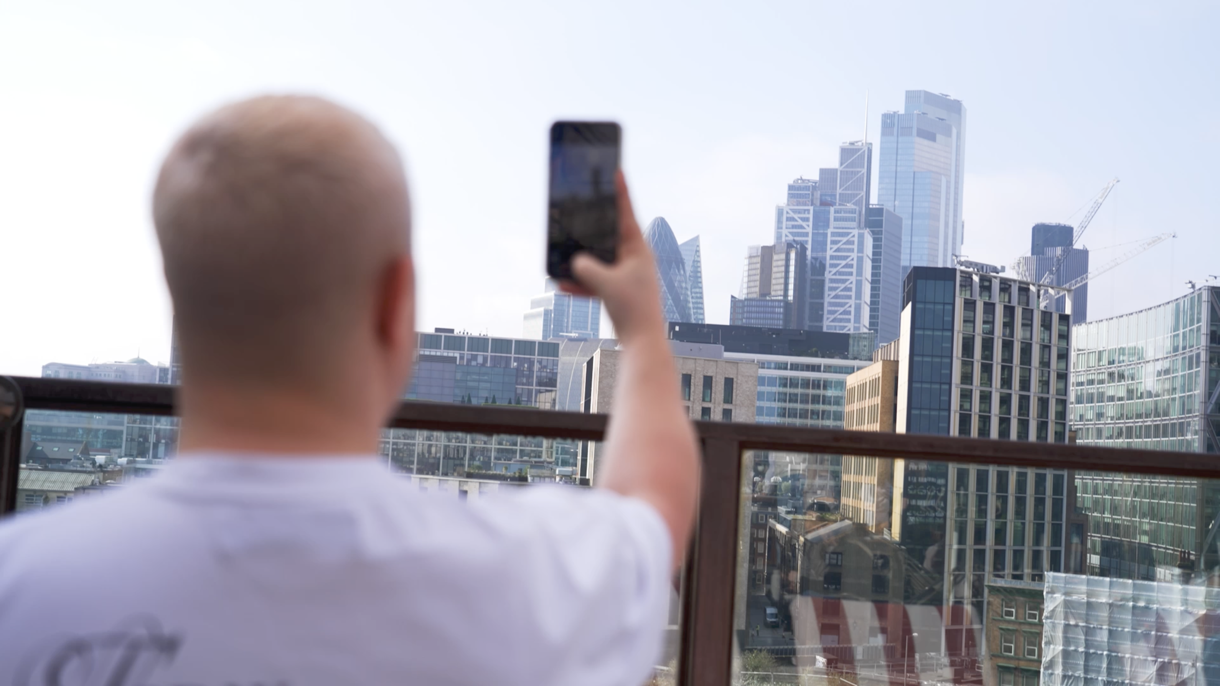 Person taking a selfie of a cityscape with tall modern buildings.