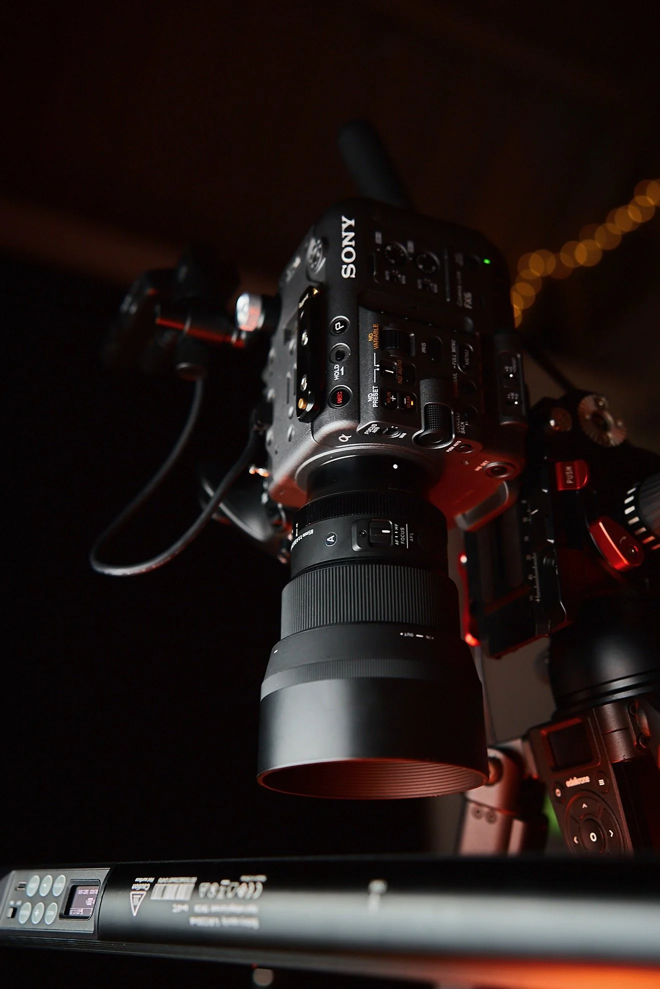 Close-up of a professional Sony camera mounted on a tripod, with a large zoom lens attached.