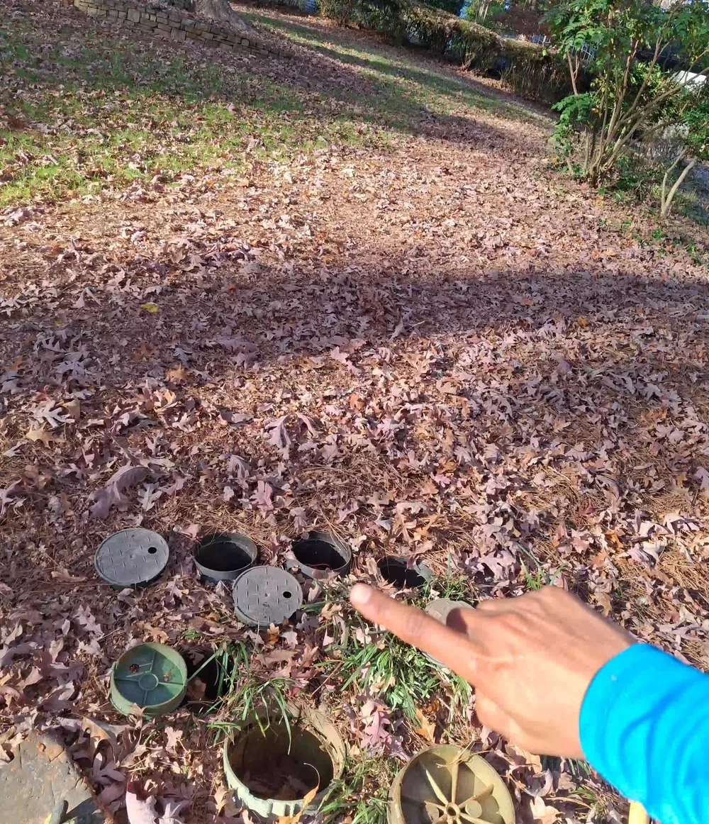 Irrigation valve boxes in a yard covered with fall leaves during a fall sprinkler shutdown in Cobb County