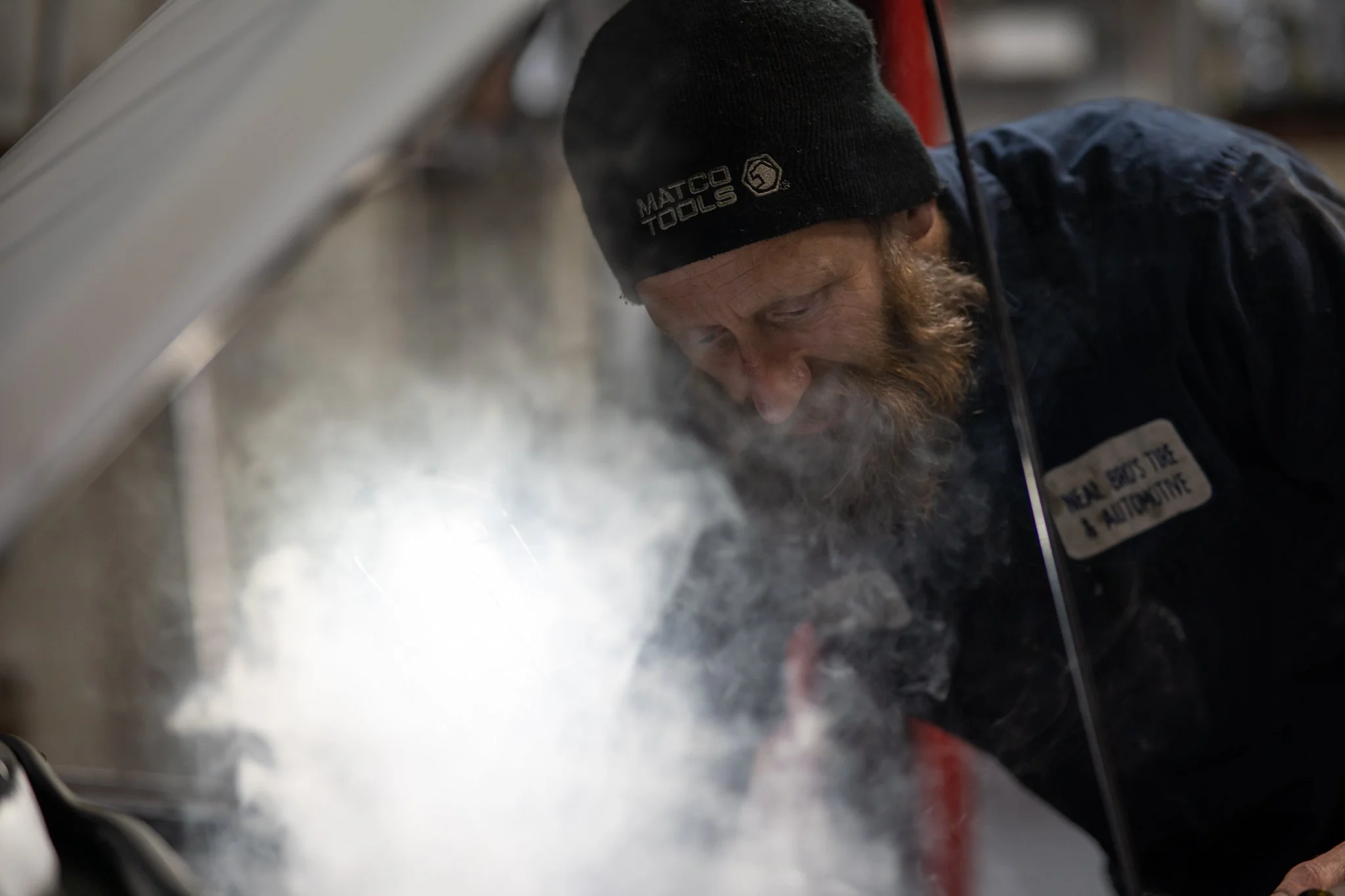 Certified mechanic inspecting vehicle engine in professional auto repair shop