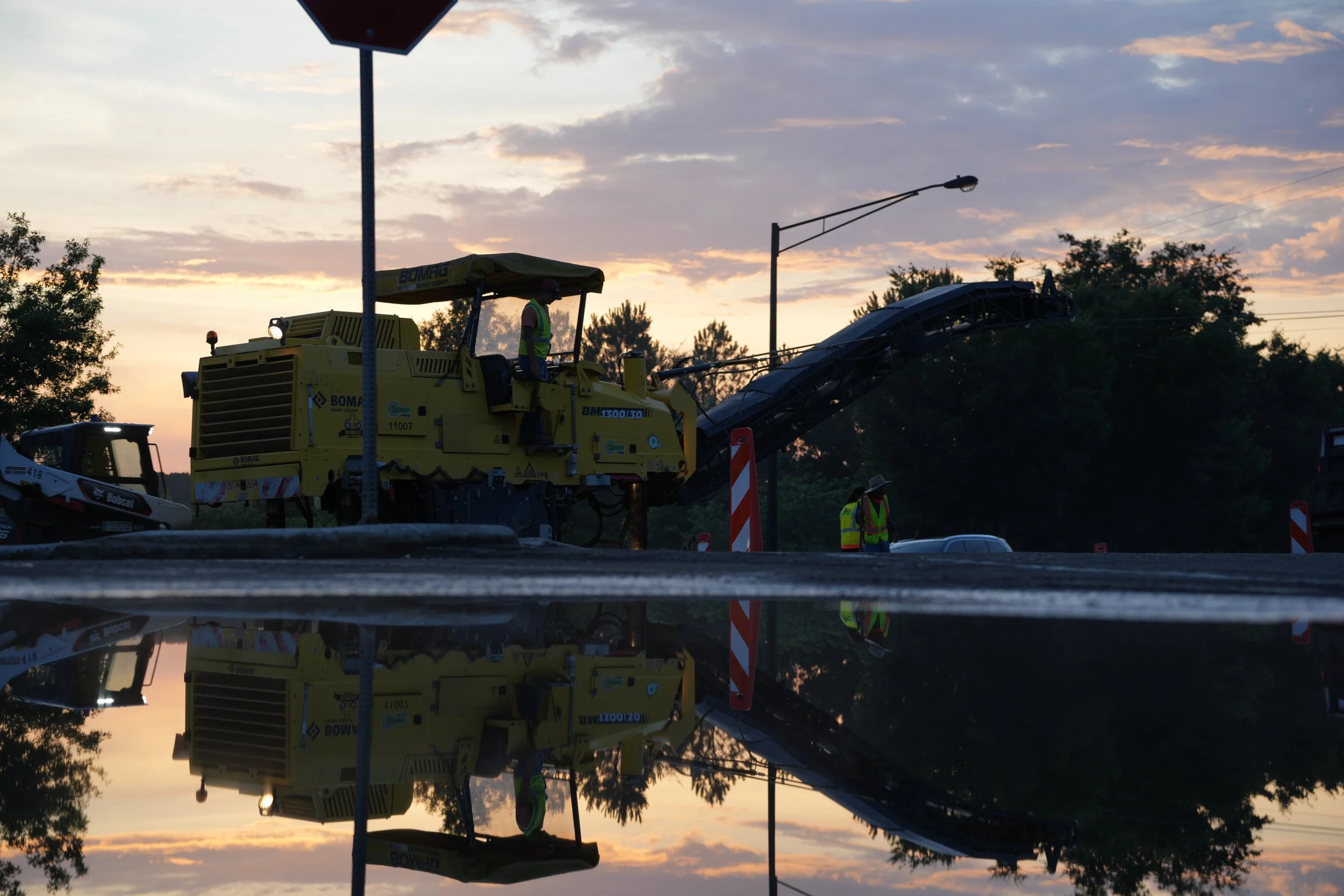 Construction workers operating asphalt paving machine during roadwork