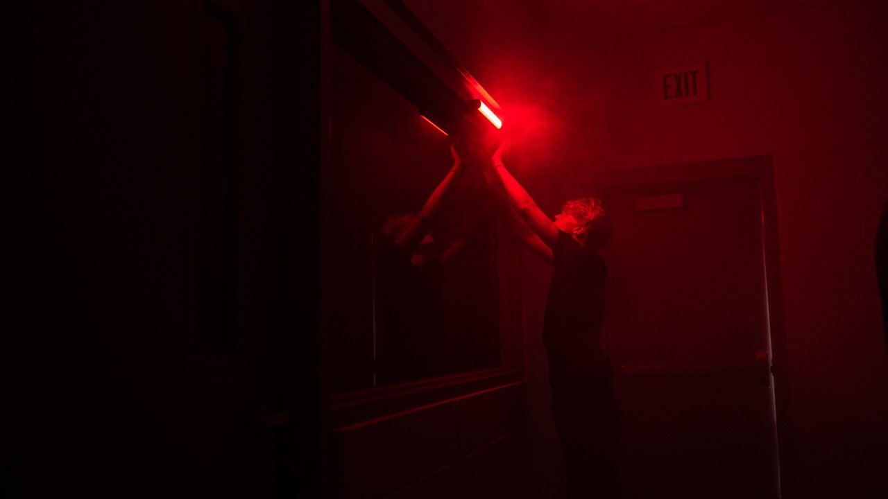 Key Grip mounts a light in a dark locker room scene.