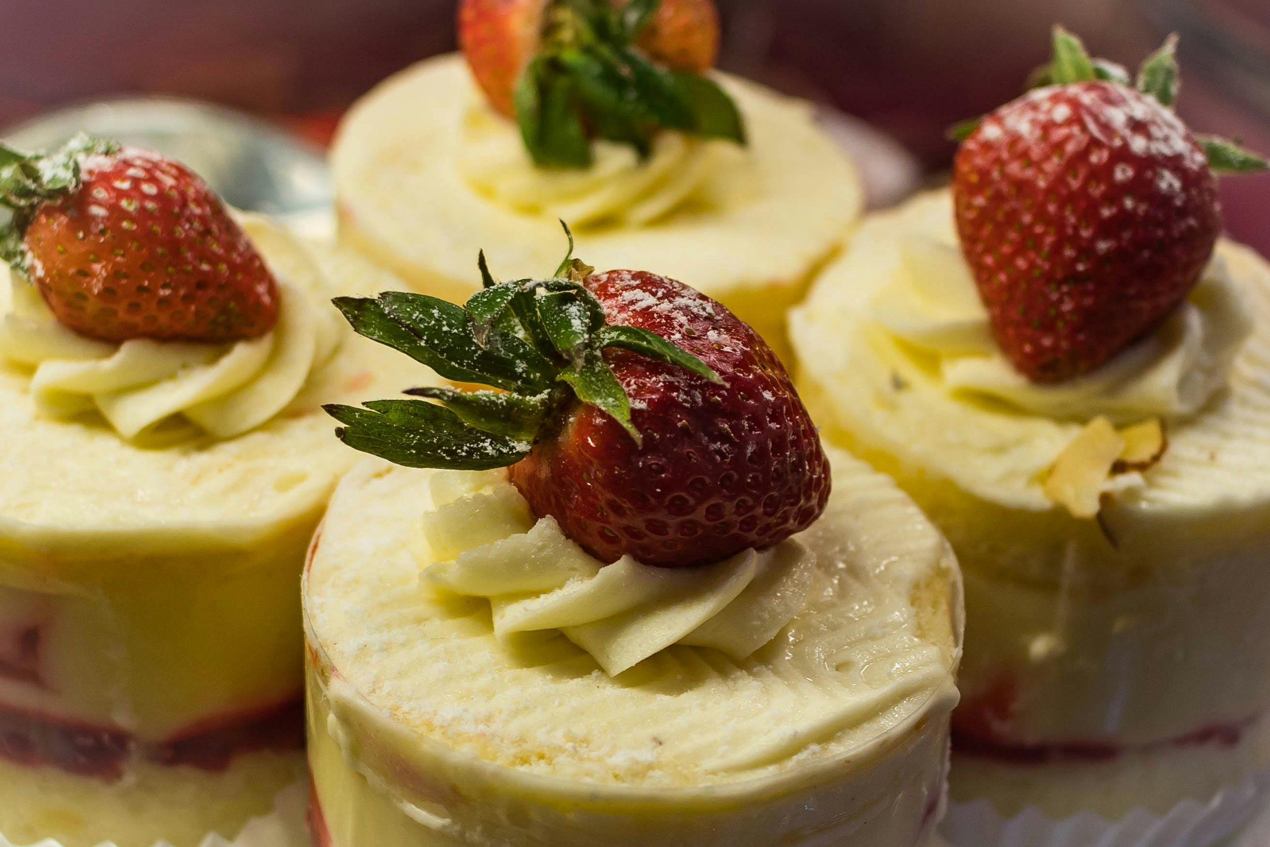 Close-up of mini strawberry shortcakes topped with strawberries and mint leaves.