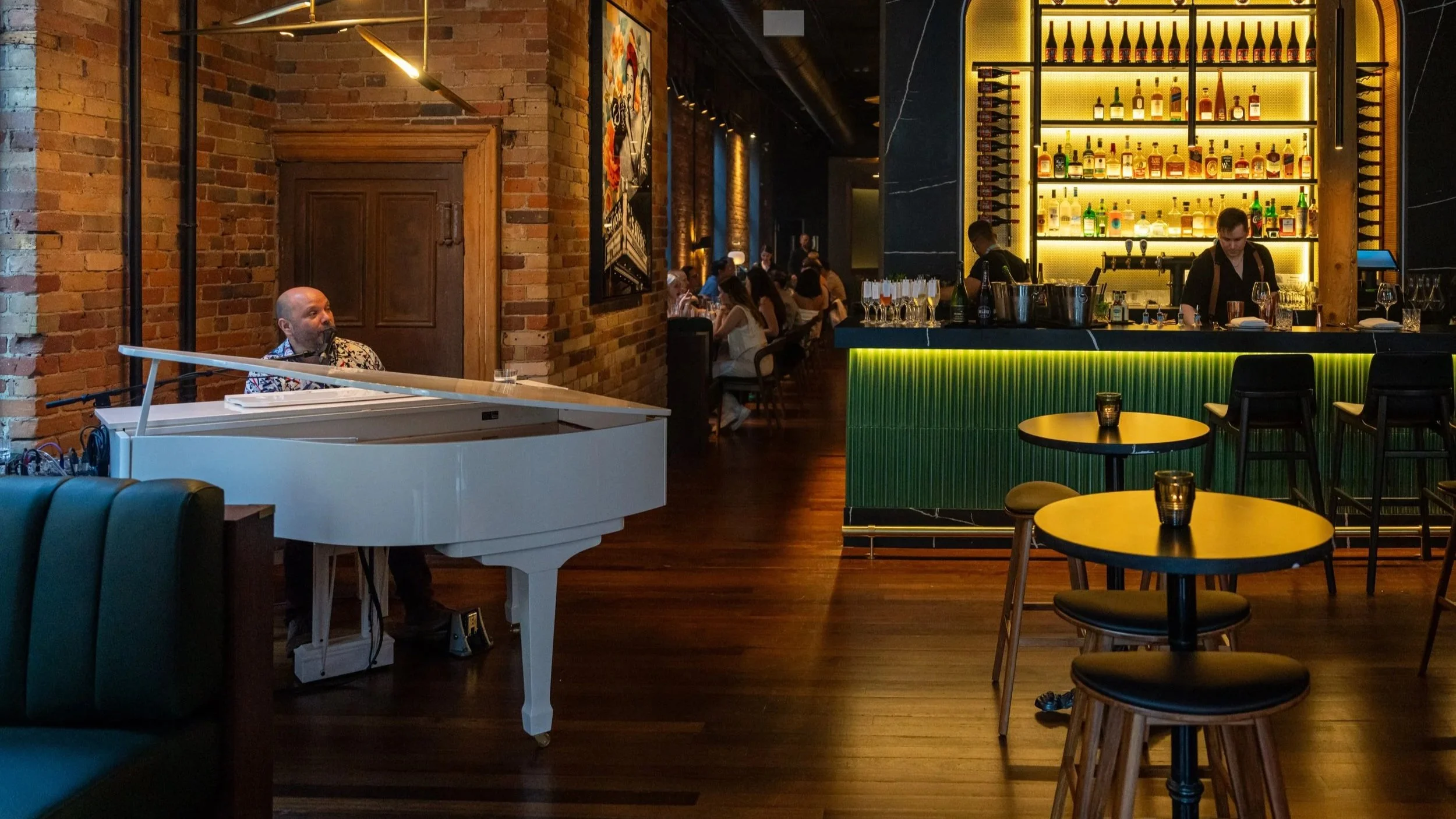 Pianist at the white grand piano beside the marble bar at The Berczy Tavern, a live piano bar and restaurant in Old Town Toronto near St. Lawrence Market