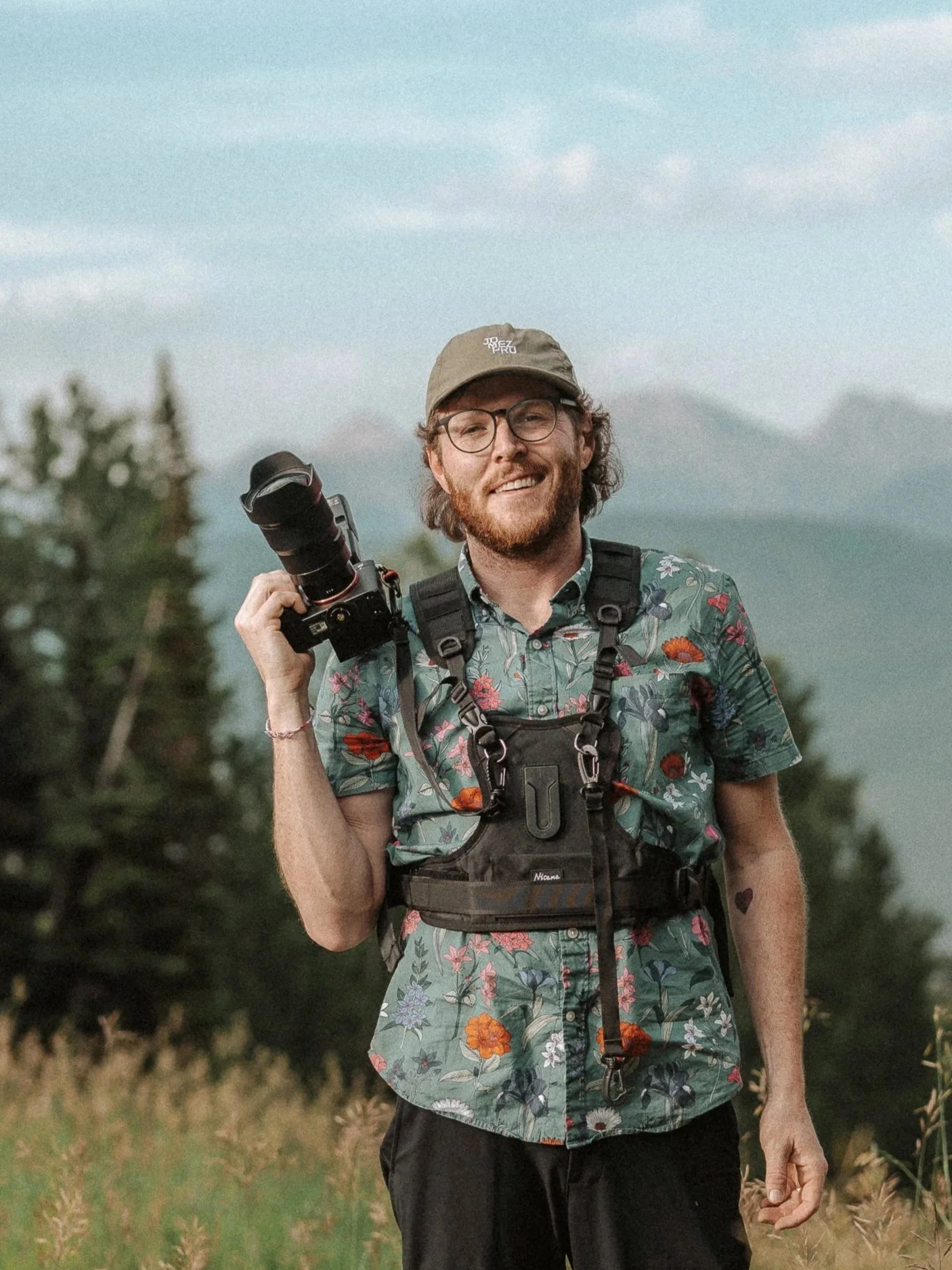 A portrait of photographer Sam Ehrnstein holding a camera.