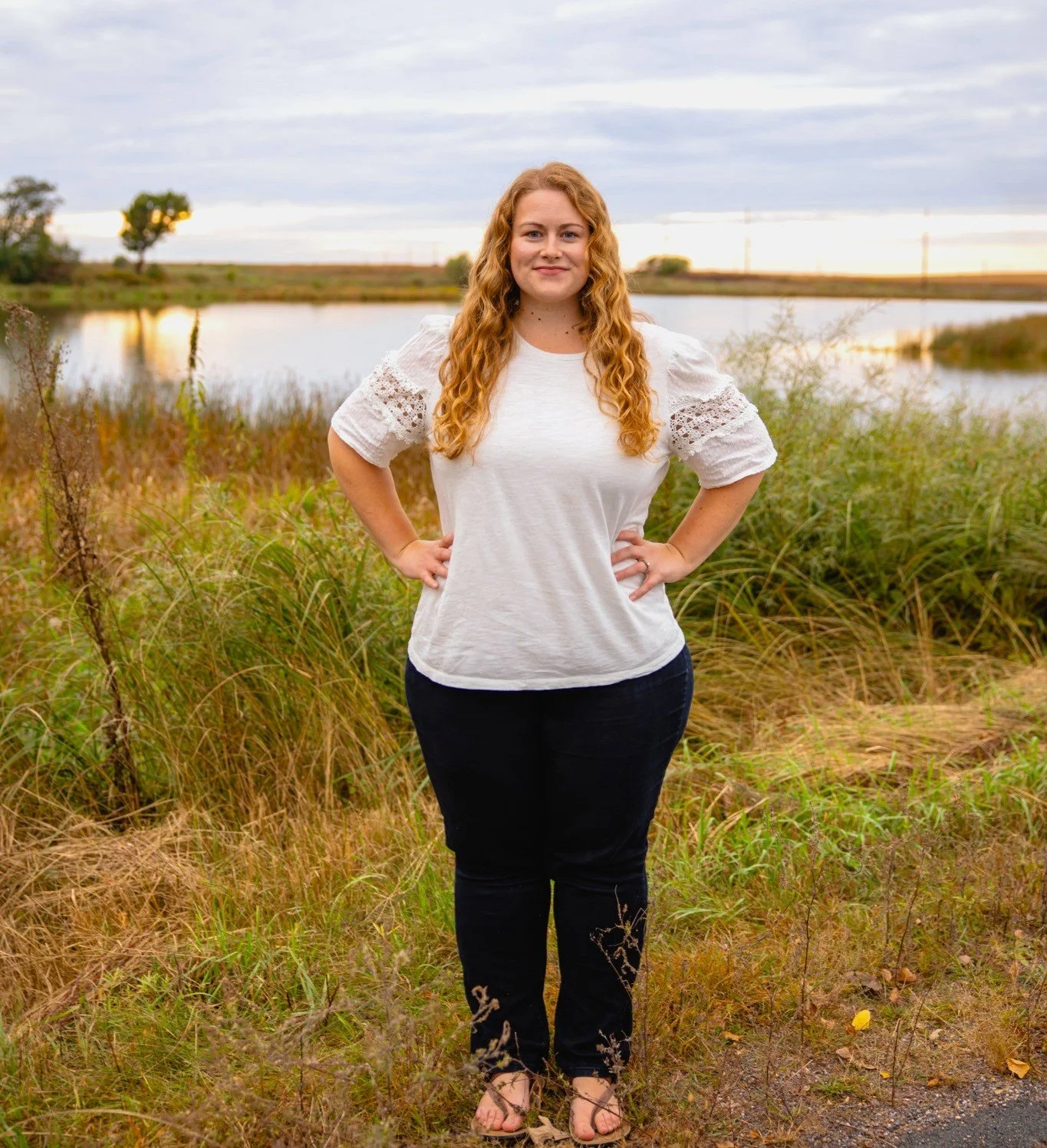 Natasha Bradt, Founder of 3 Lakes Bookkeeping, standing proudly outdoors by a calm lake at the Three Lakes Wildlife Area in New Richmond, Wisconsin, representing financial balance and peace of mind.