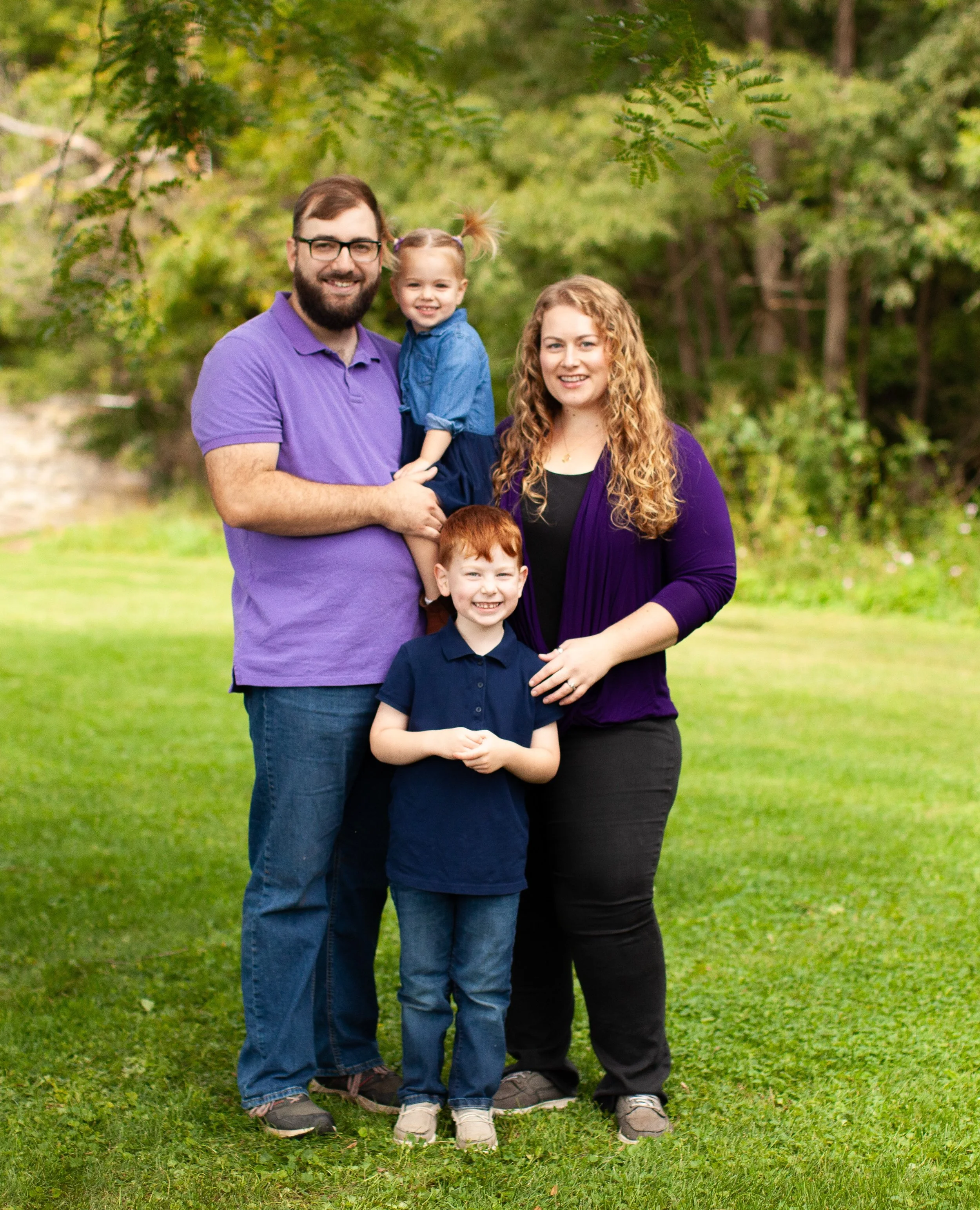 Natasha Bradt, Founder of 3 Lakes Bookkeeping, with her husband and two children in a family portrait outdoors near Hudson, Wisconsin.