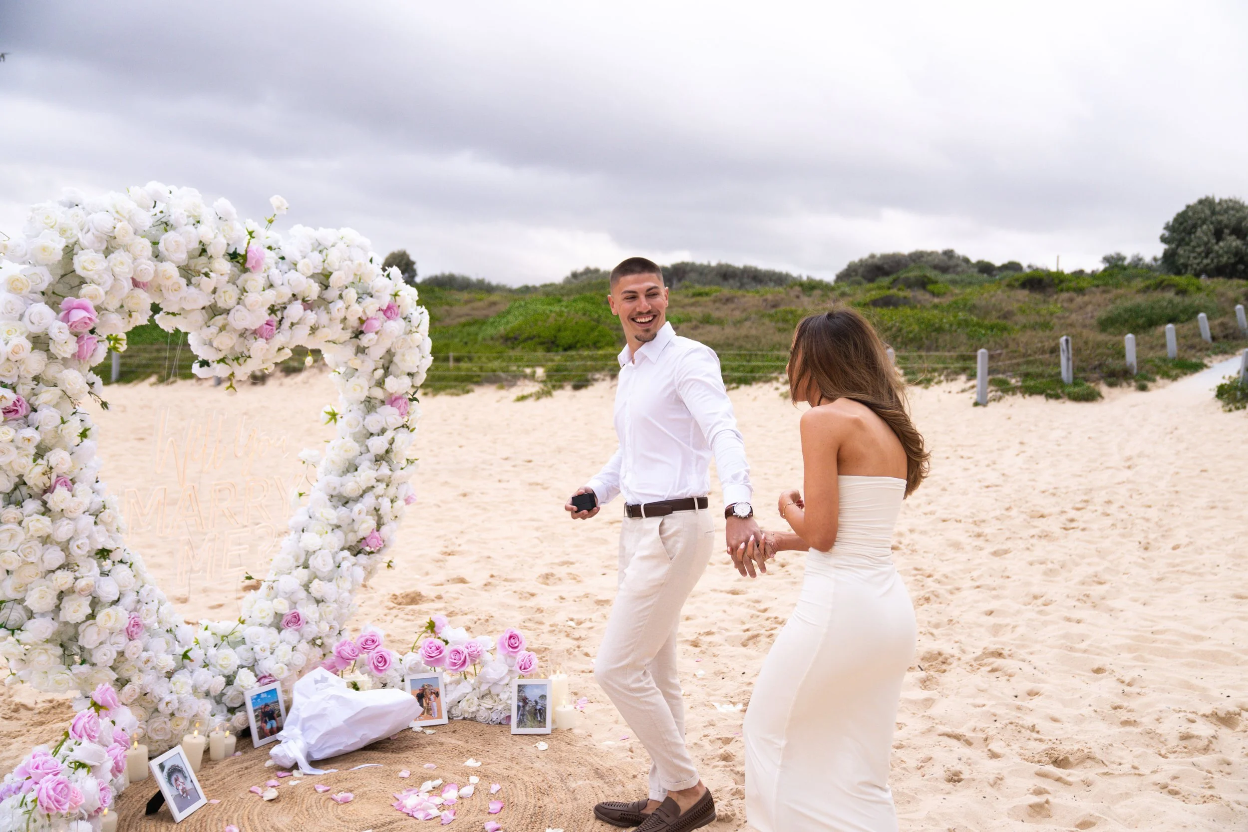 Couple’s first dance on the beach beneath a heart arch - coastal wedding photography, Sydney.