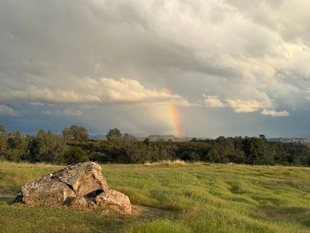 Rainbow over boulder in the Sierra foothills.