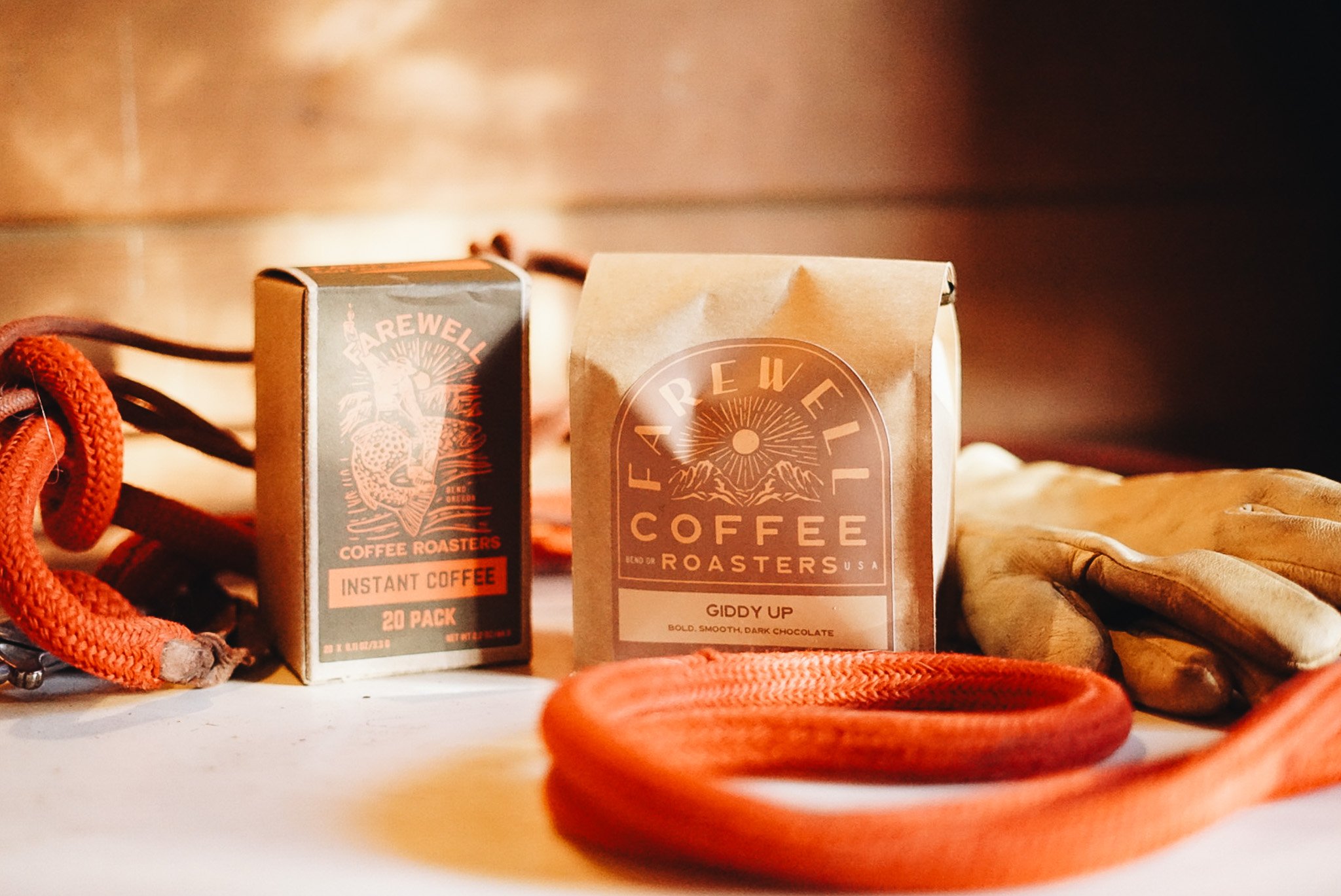 Packages of Farewell Coffee Roasters on a table with a coiled red rope and leather gloves in the background.