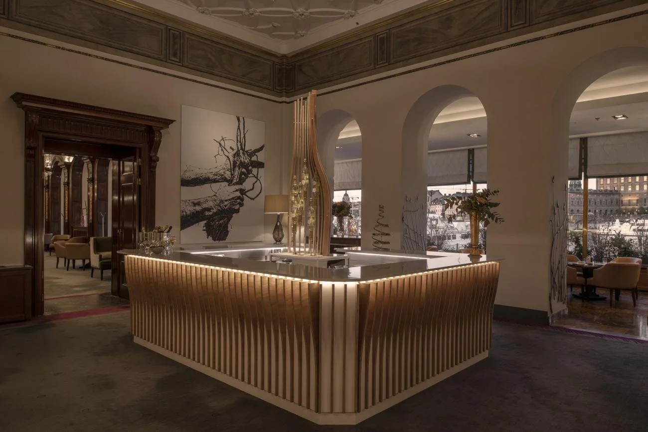 Elegant hotel lobby with a modern reception desk, large windows, artwork, and seating areas.