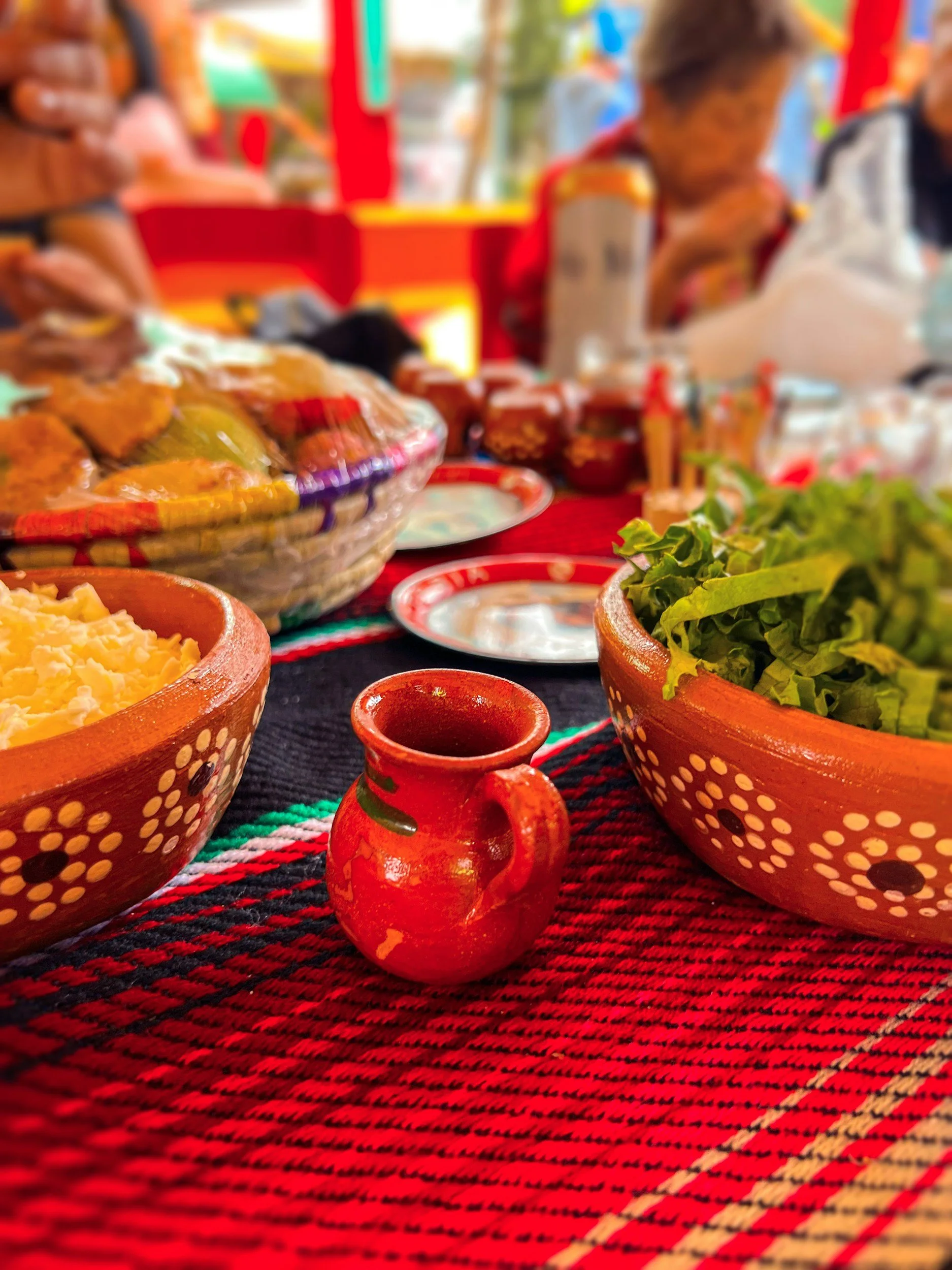 Mexican table setting with traditional pottery, food, and a patterned tablecloth