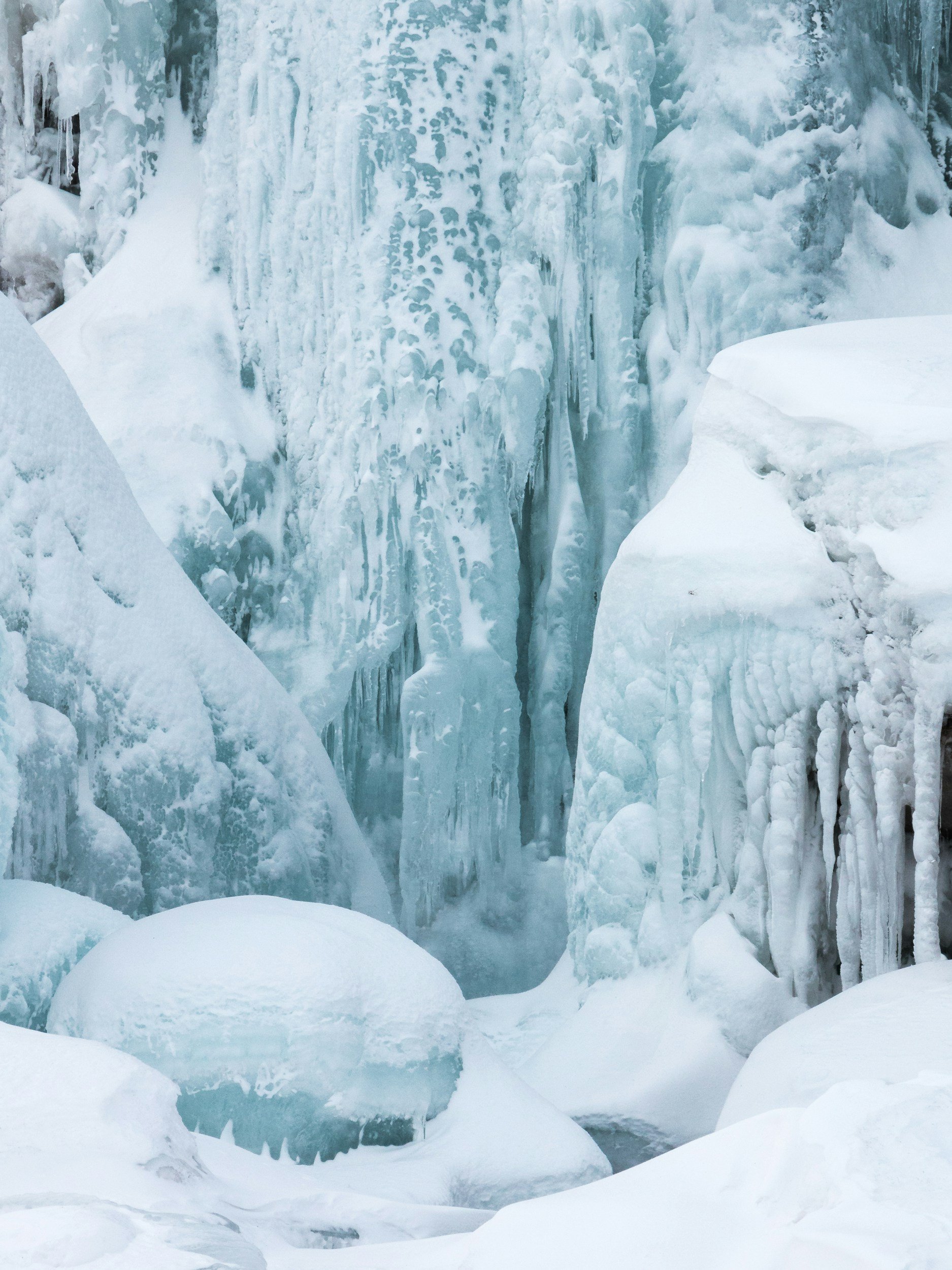 Close-up of a natural icy terrain with frozen water formations, snow, and icicles creating a winter landscape.