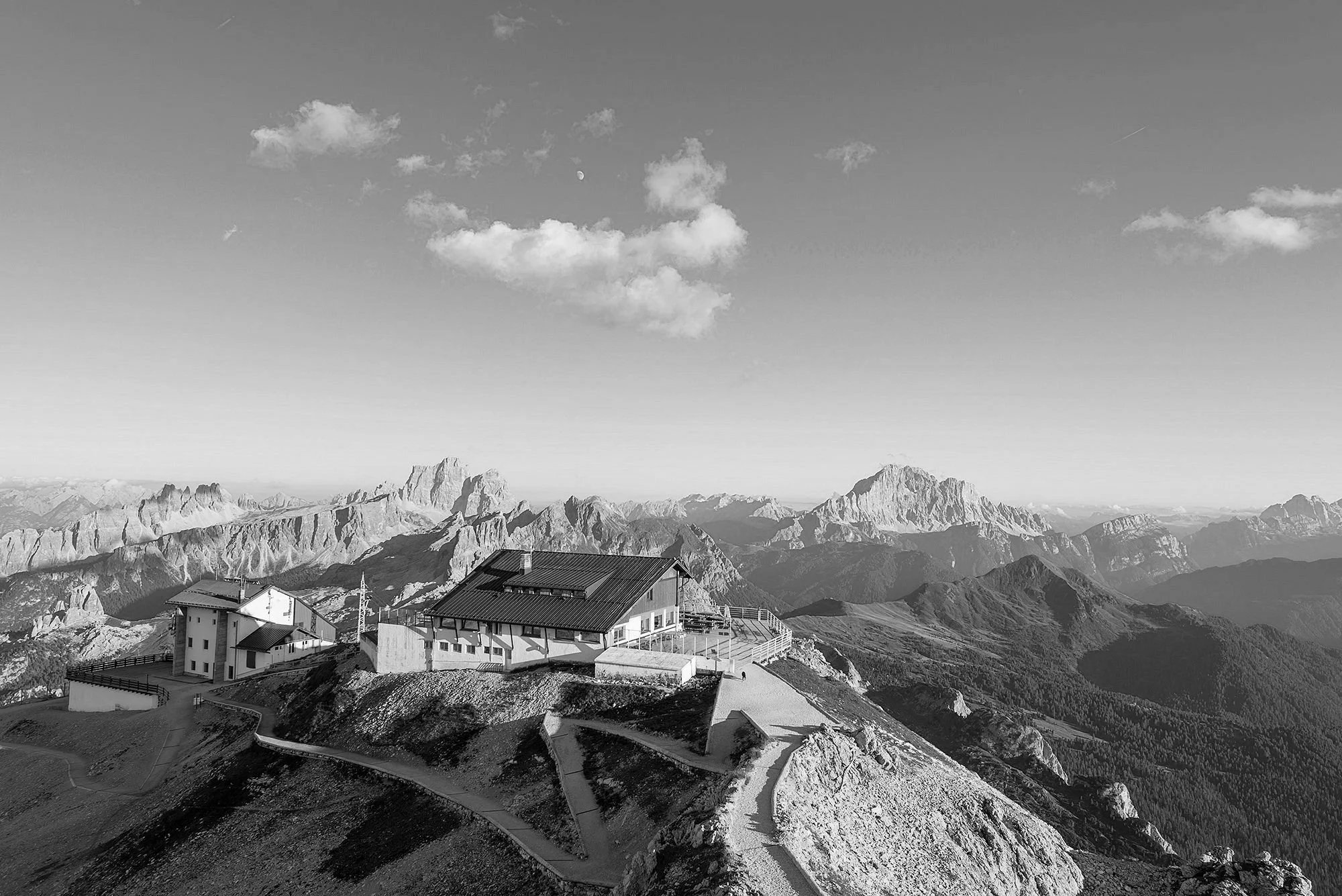 Black and white photo of a mountain peak, showcasing rugged terrain and dramatic sky contrasts.