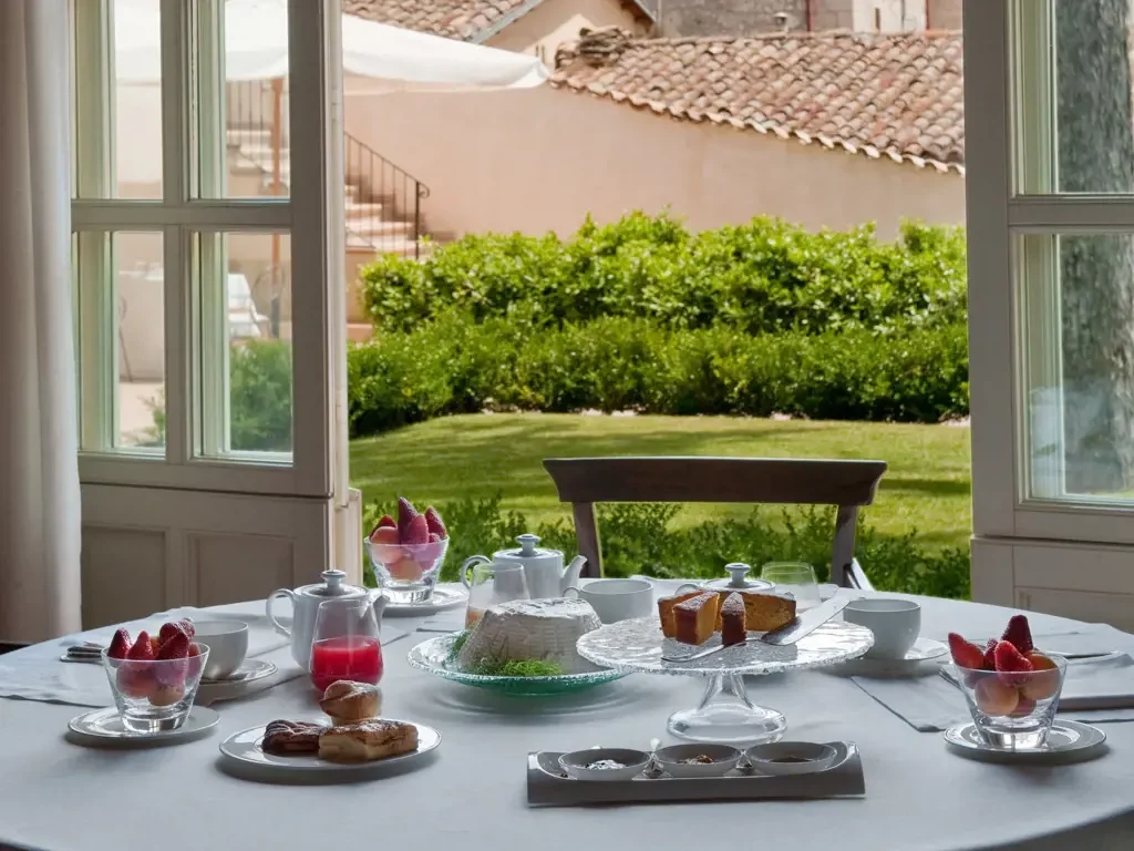 Rooftop terrace with white umbrellas and potted plants, view of domed building in the background at sunset.