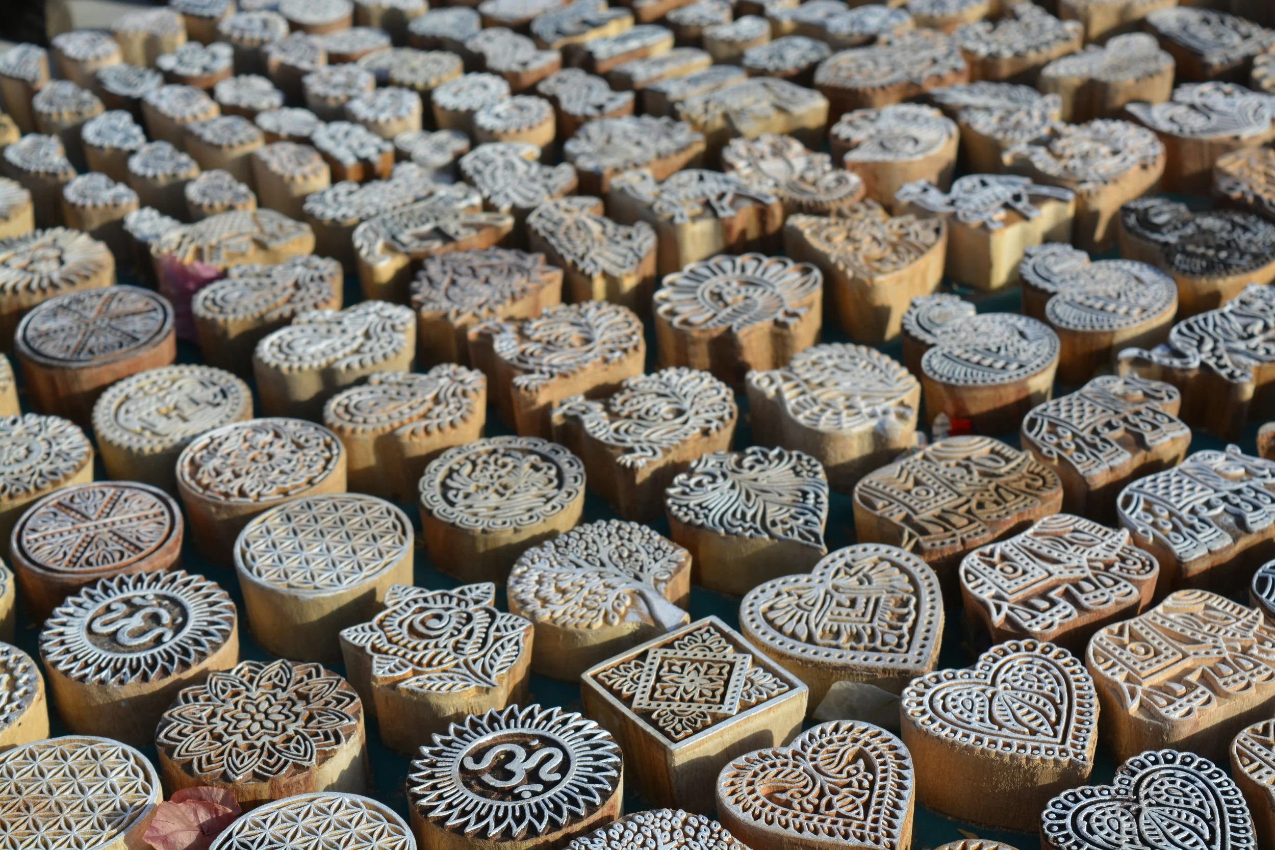 Various intricately carved wooden blocks for fabric printing, arranged in rows.
