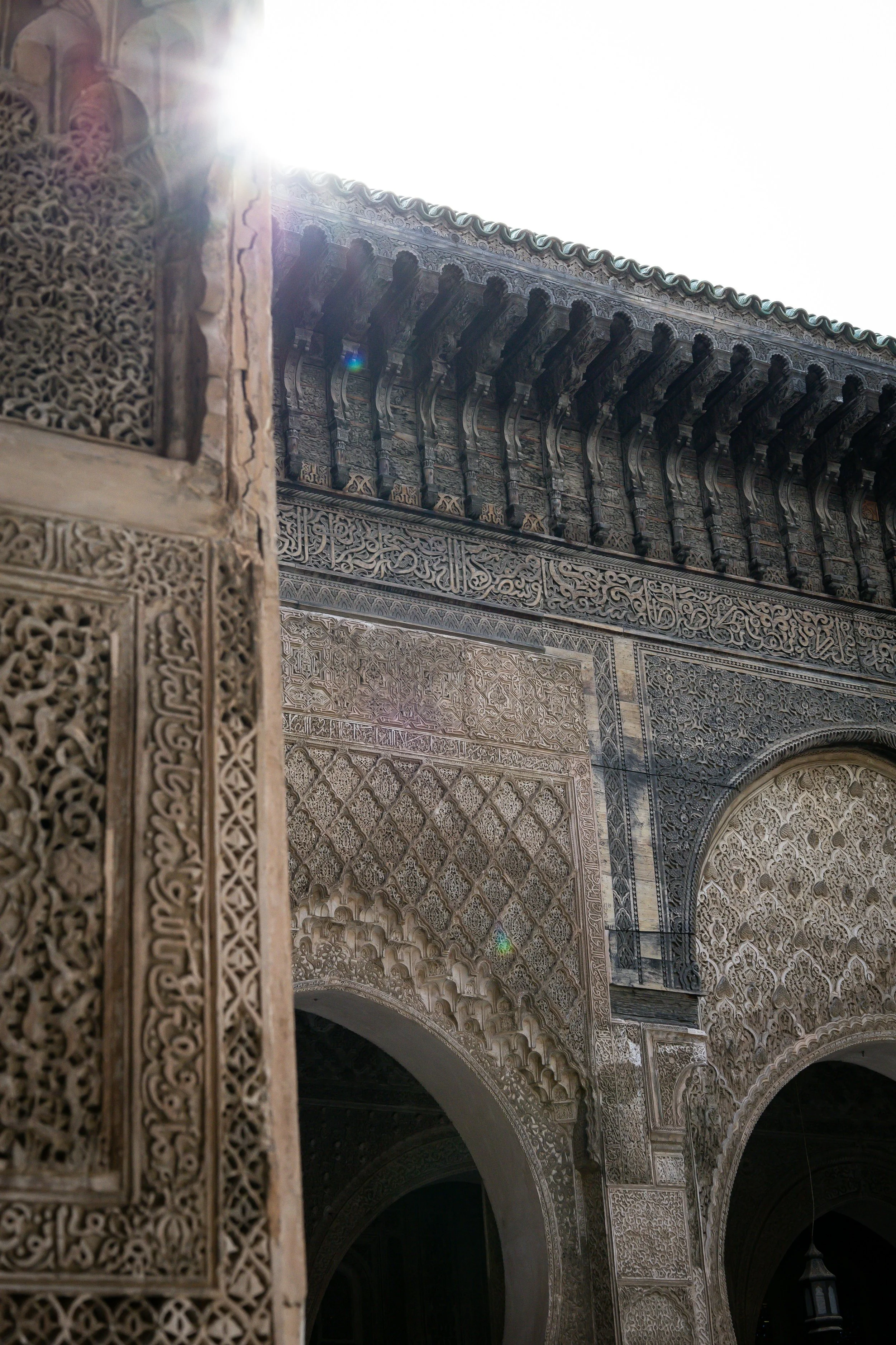 Ornate Islamic architectural details with intricate carvings and sunlight shining over the top.