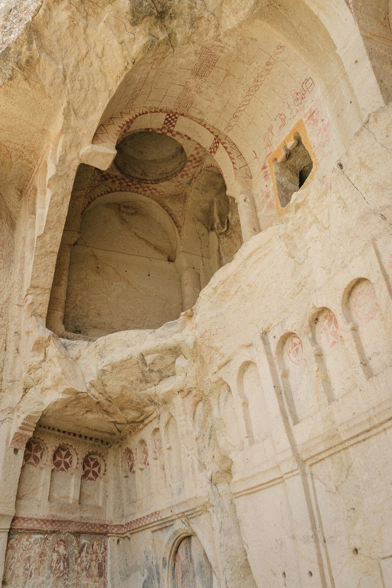 Interior of ancient stone structure with decorative arches, frescoes, and carved details on the walls and ceiling.