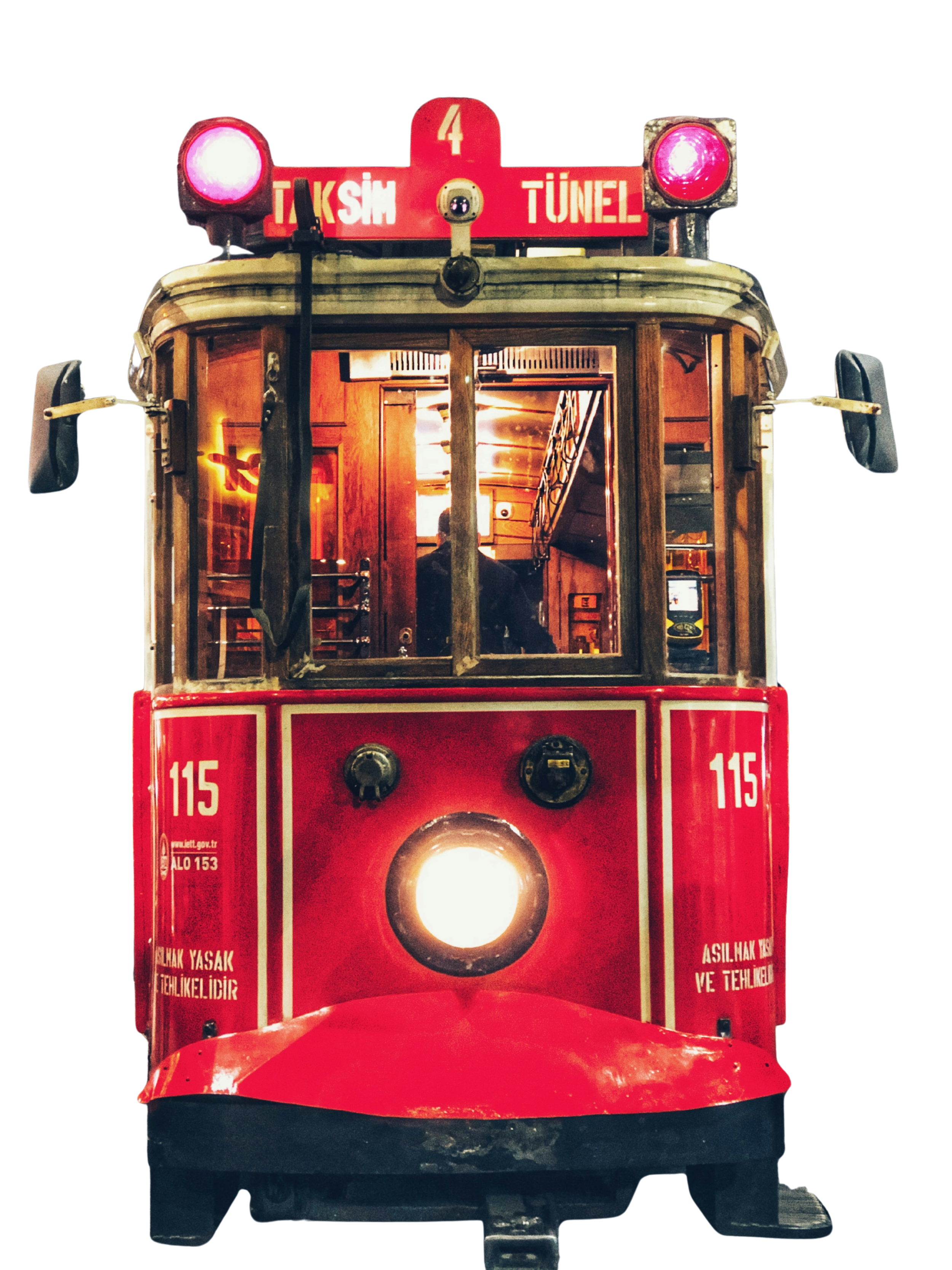 Front view of a vintage red tram with the sign 'Taksim Tünel' on top, illuminated from within, showing the interior with warm lighting.