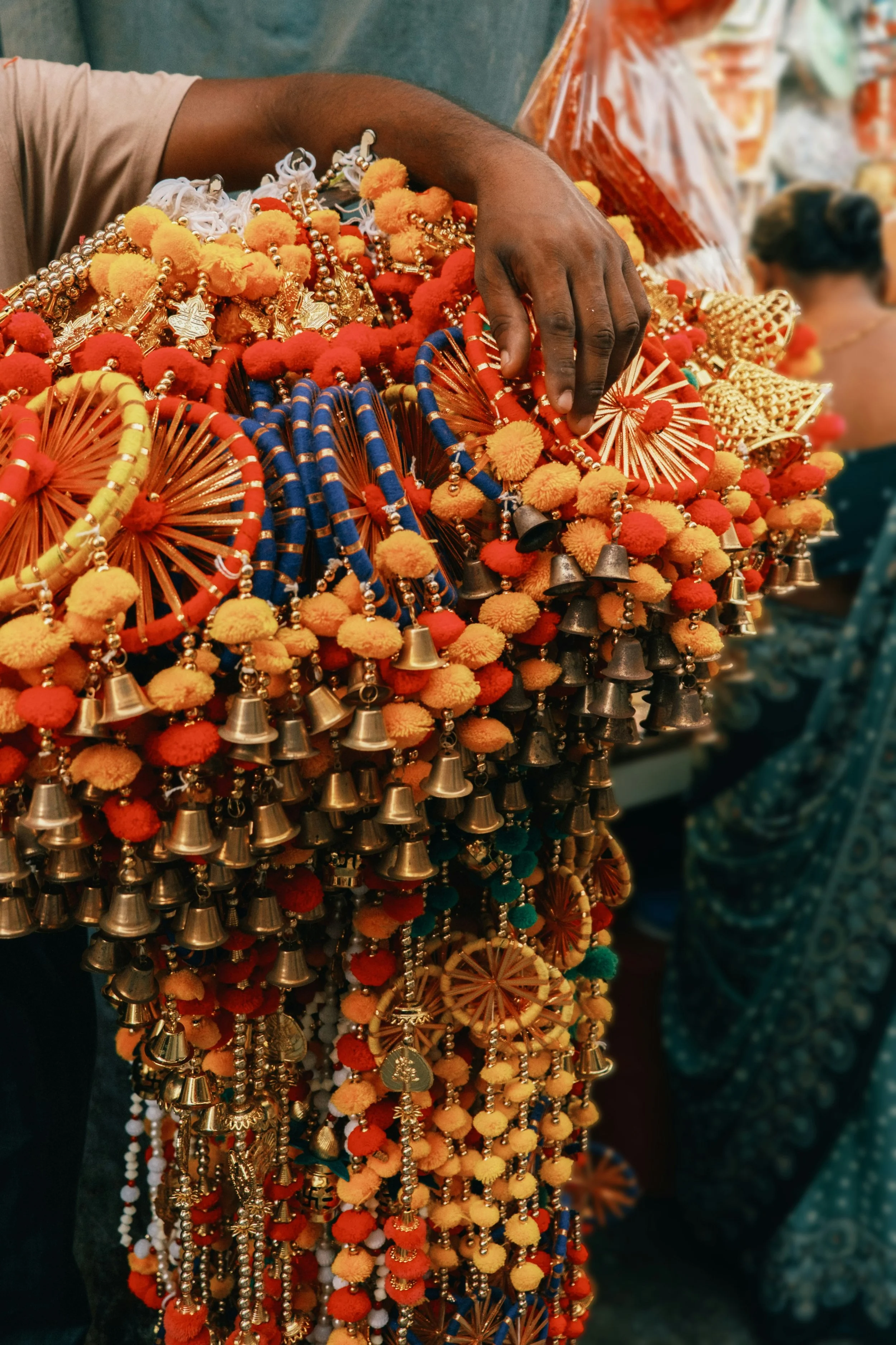 Colorful Indian decorative items with pom-poms, bells, and beads.