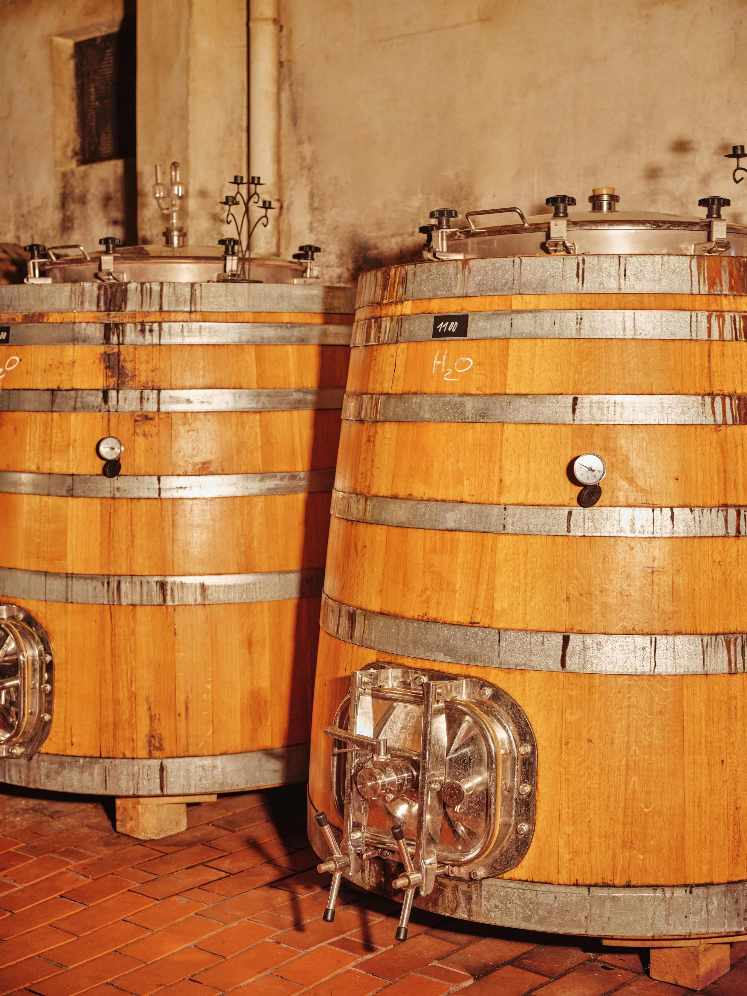 Large wooden fermentation barrels with metal bands in a winery.