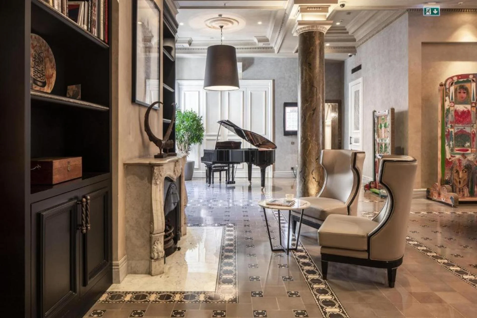 Elegant hotel lobby with high ceilings, marble fireplaces, plush beige chairs, a black grand piano near large windows, decorative columns, and ornate flooring.
