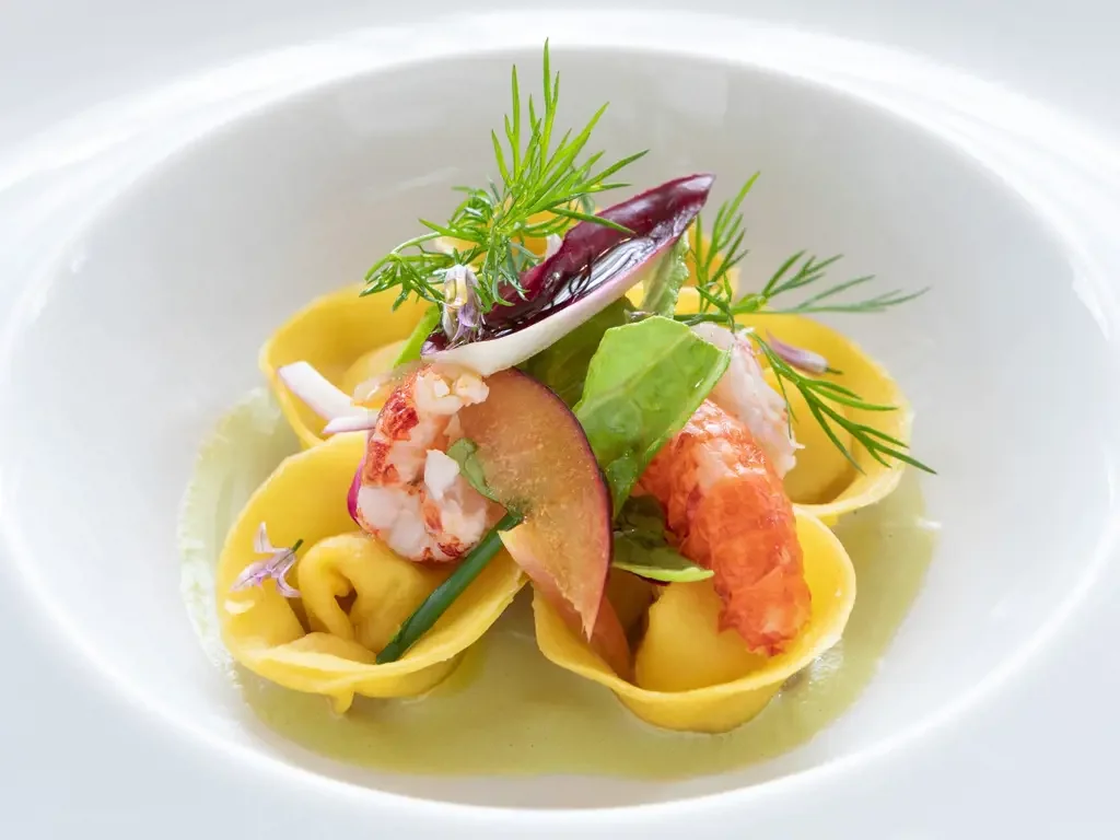 Rooftop restaurant with tables set for dining, overlooking a cityscape featuring historic buildings and domes at sunset.