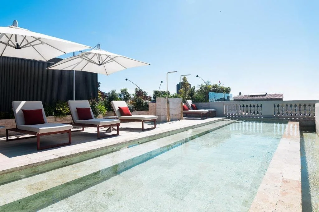Luxurious bathroom with marble walls and floor, wooden vanity, glass shower, and bathtub.