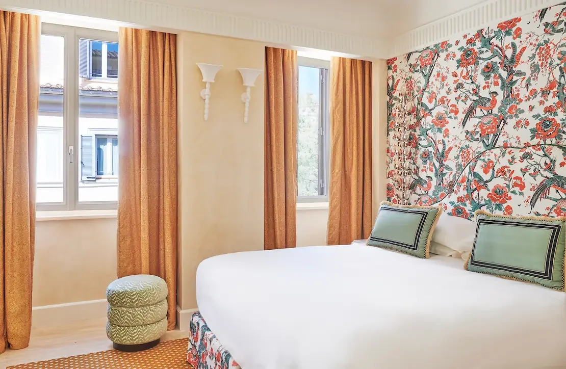 Rooftop terrace with white umbrellas and potted plants, view of domed building in the background at sunset.