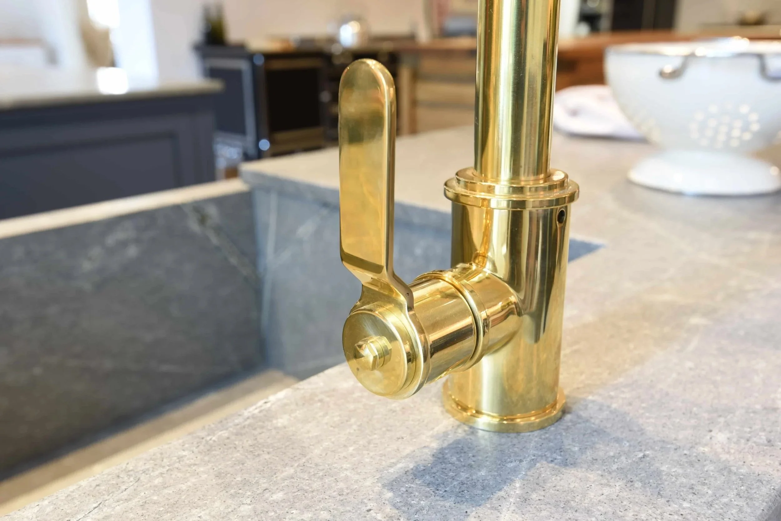Nahaufnahme eines goldenen Wasserhahns und einer Küchenarbeitsplatte aus Granit mit dazu passender Spüle.
