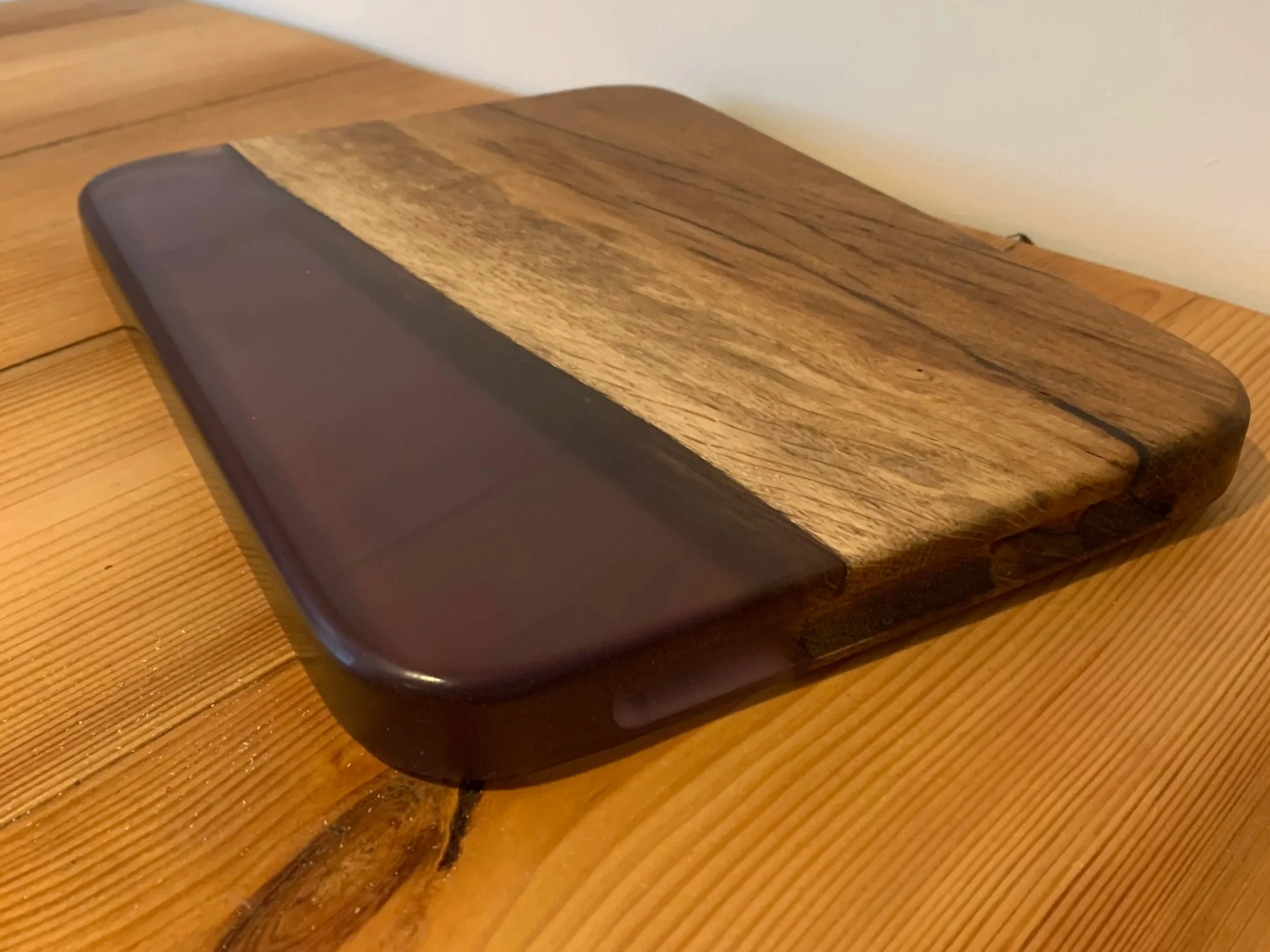 Wood and resin serving board with a glossy reddish‑brown resin section and natural hardwood grain.