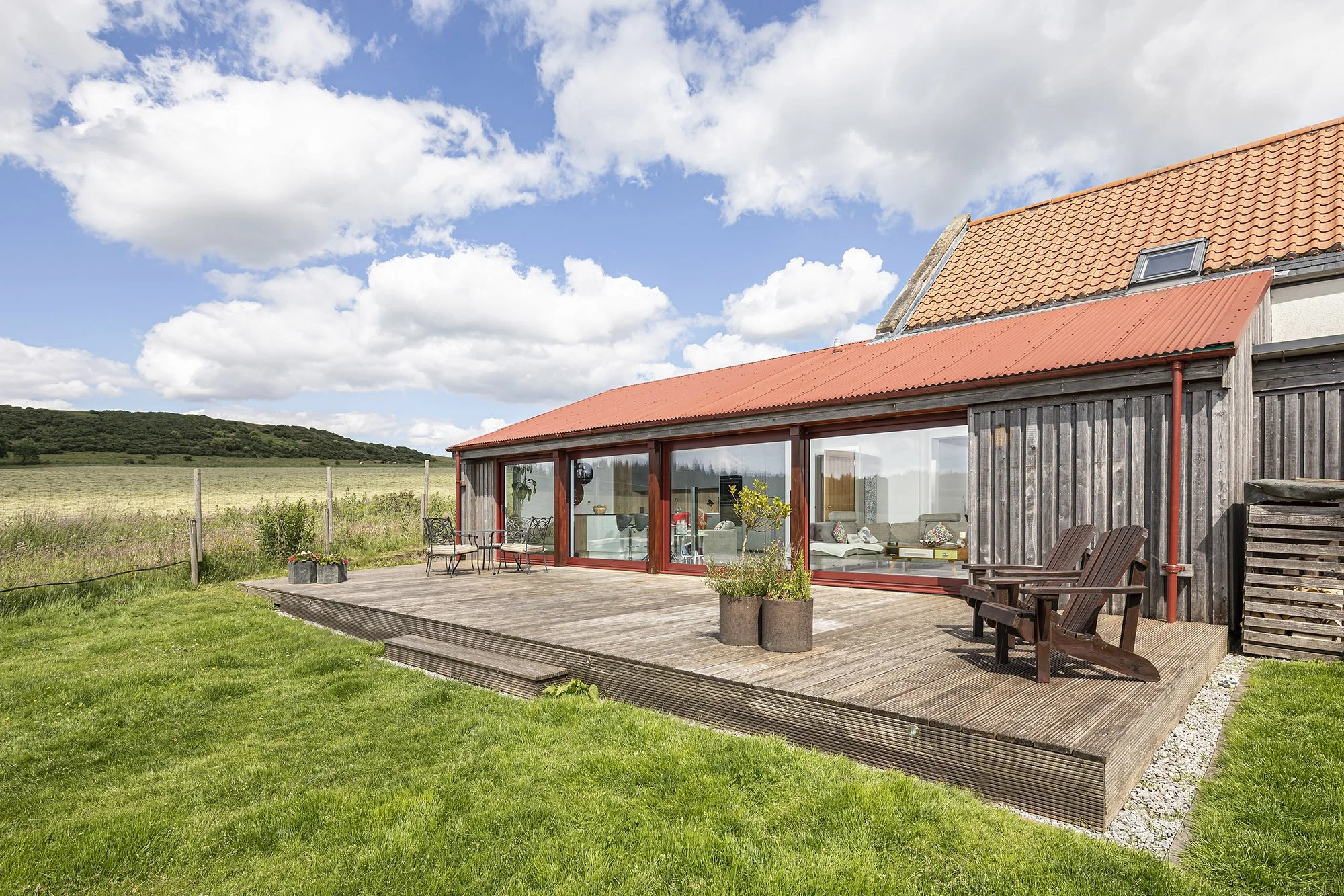 Rural timber clad self-build home with red metal roof