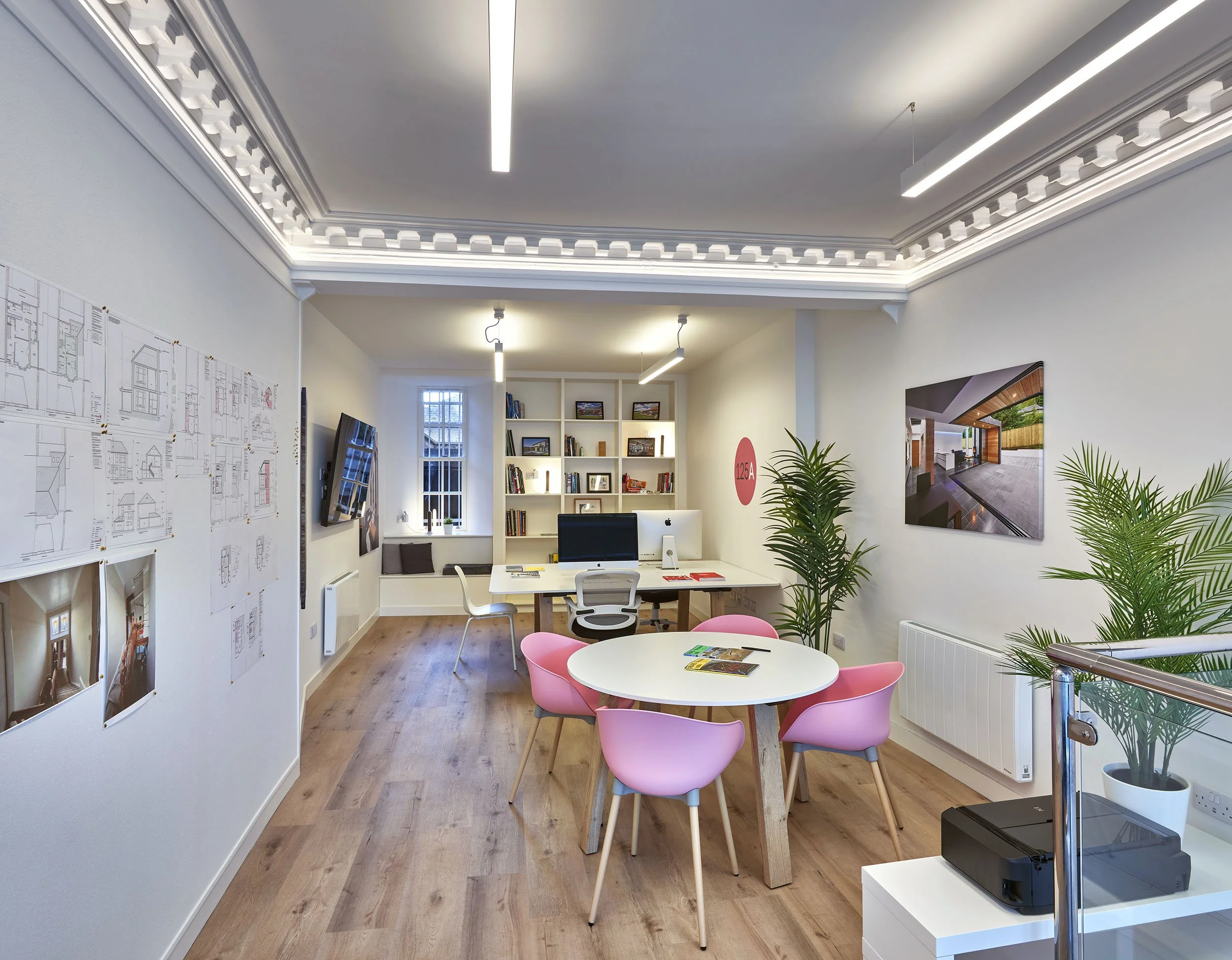 Interior of 125A Nethergate, showing the 125Architects studio with meeting table, pink chairs, pinned drawings, project photographs and workstations.